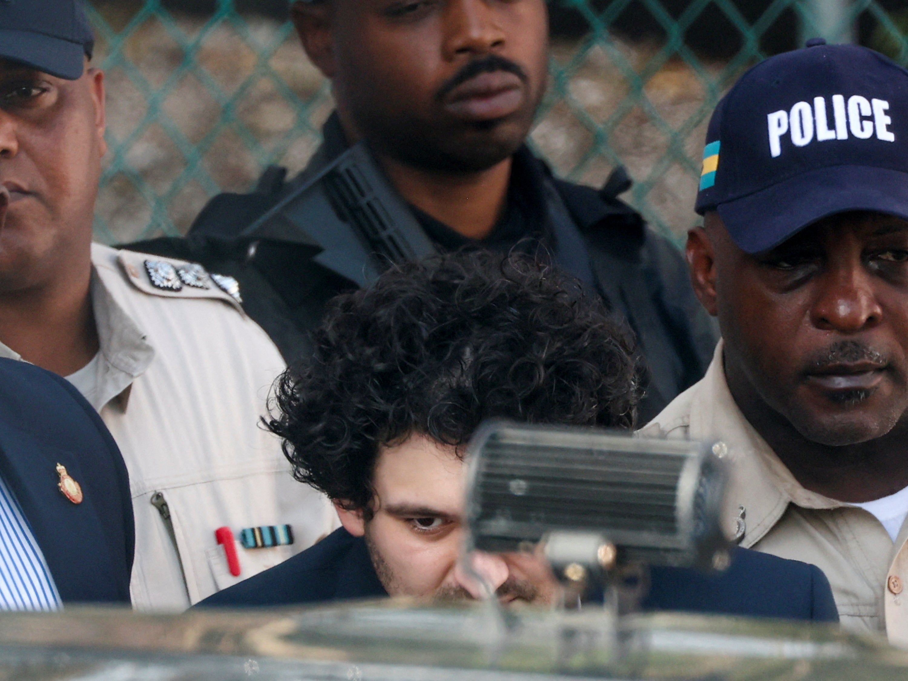 Sam Bankman-Fried is escorted out of the court building in Nassau on Monday