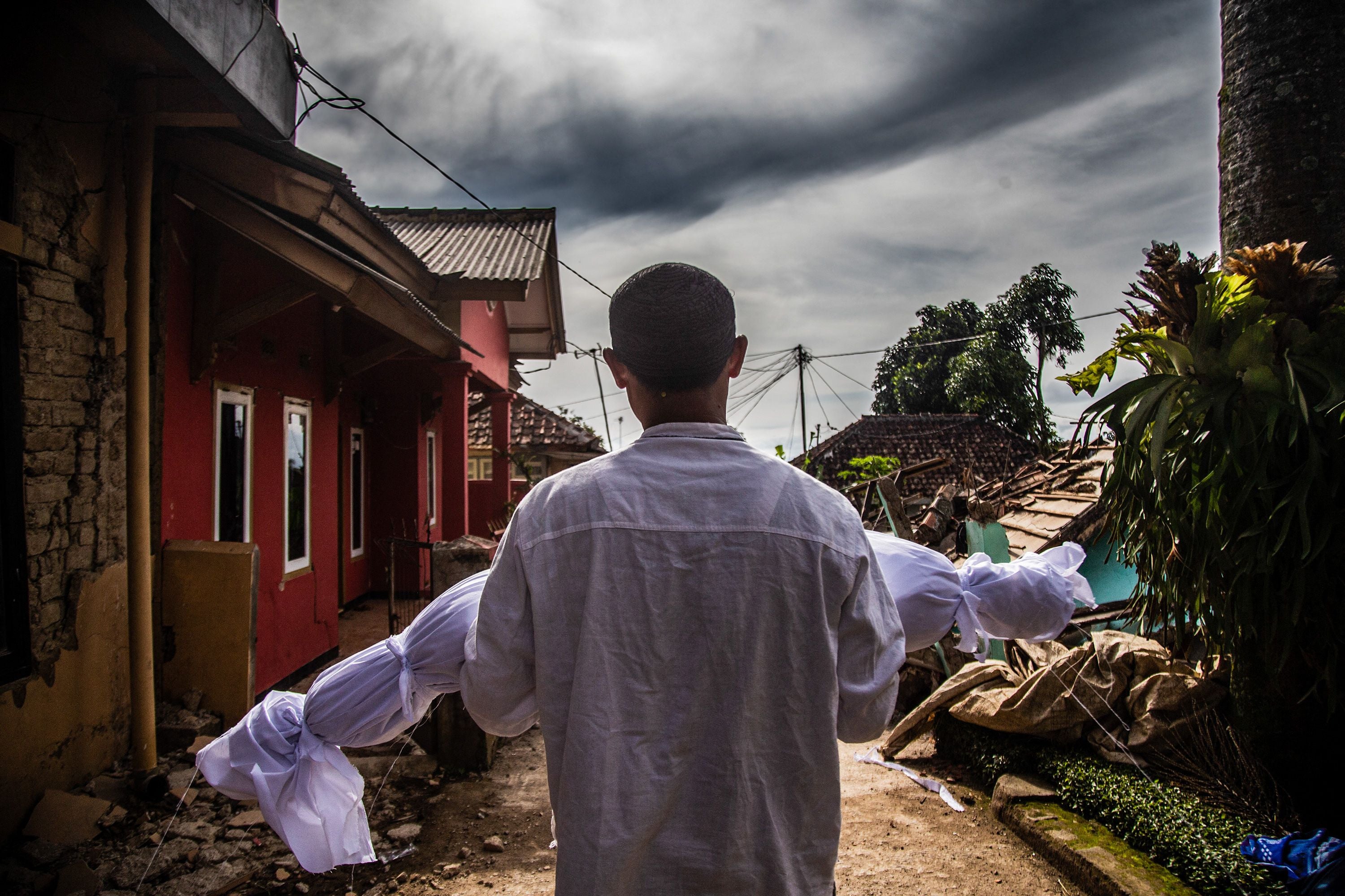 A villager carries the body of his dead son following a 5.6-magnitude earthquake that killed at least 162 people, with hundreds injured and others missing in Cianjur, Indonesia