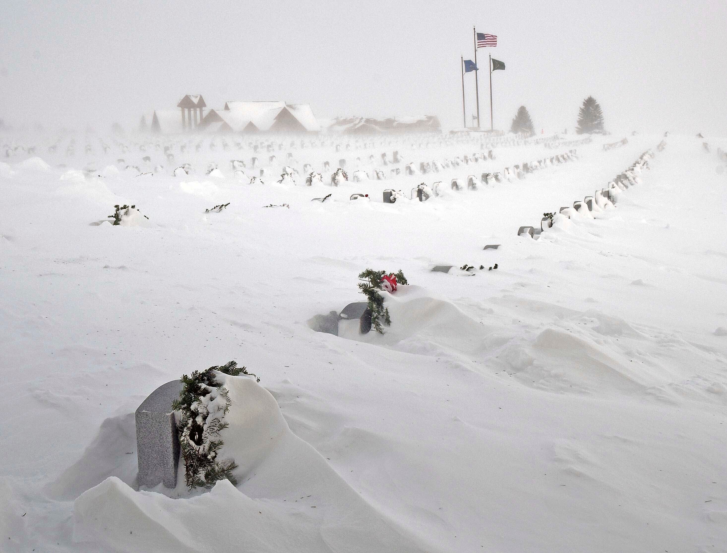 Rows of headstones at the North Dakota Veterans Cemetery are blanketed by drifting snow Thursday
