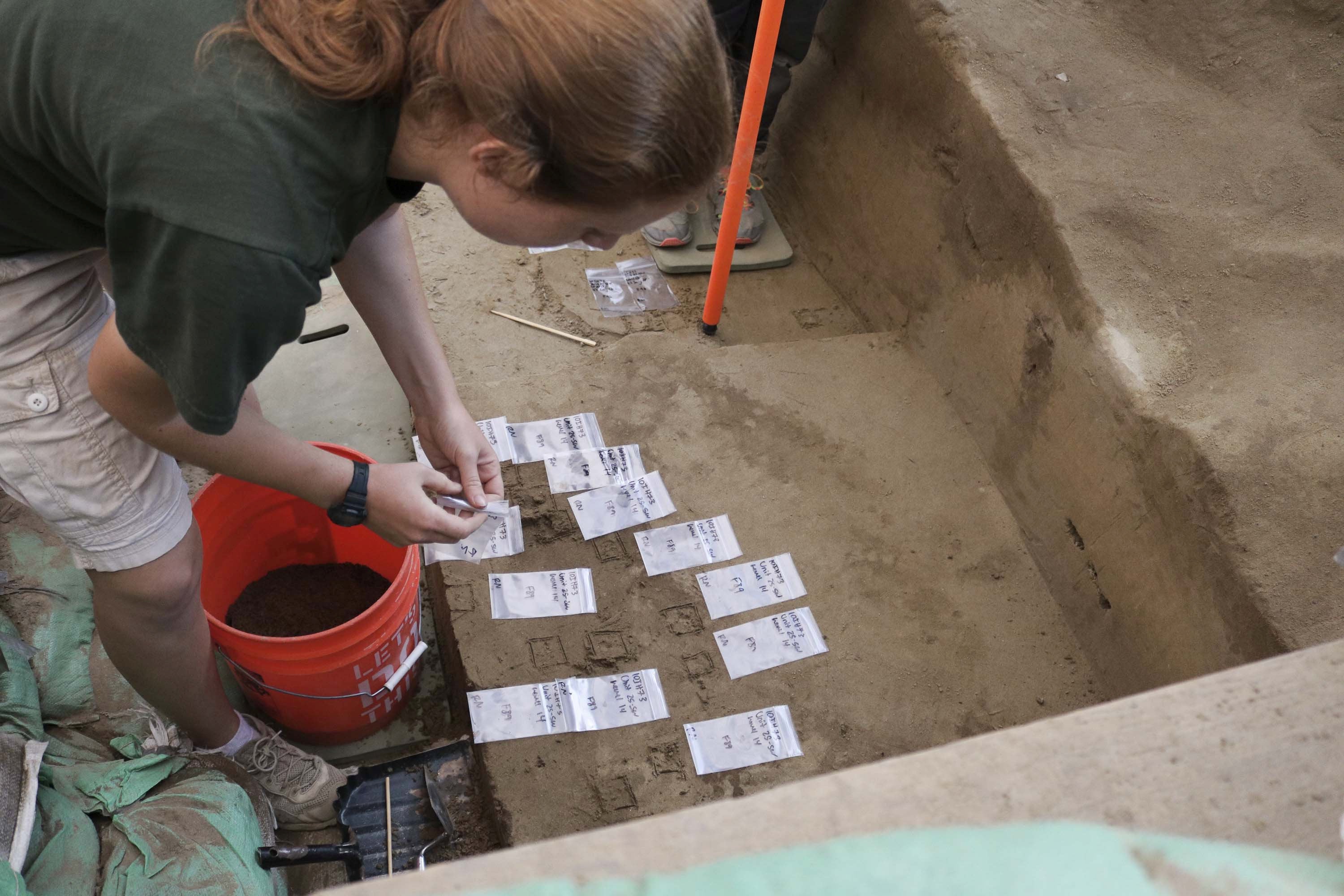 An excavator at work recording artifacts excavated from a pit feature