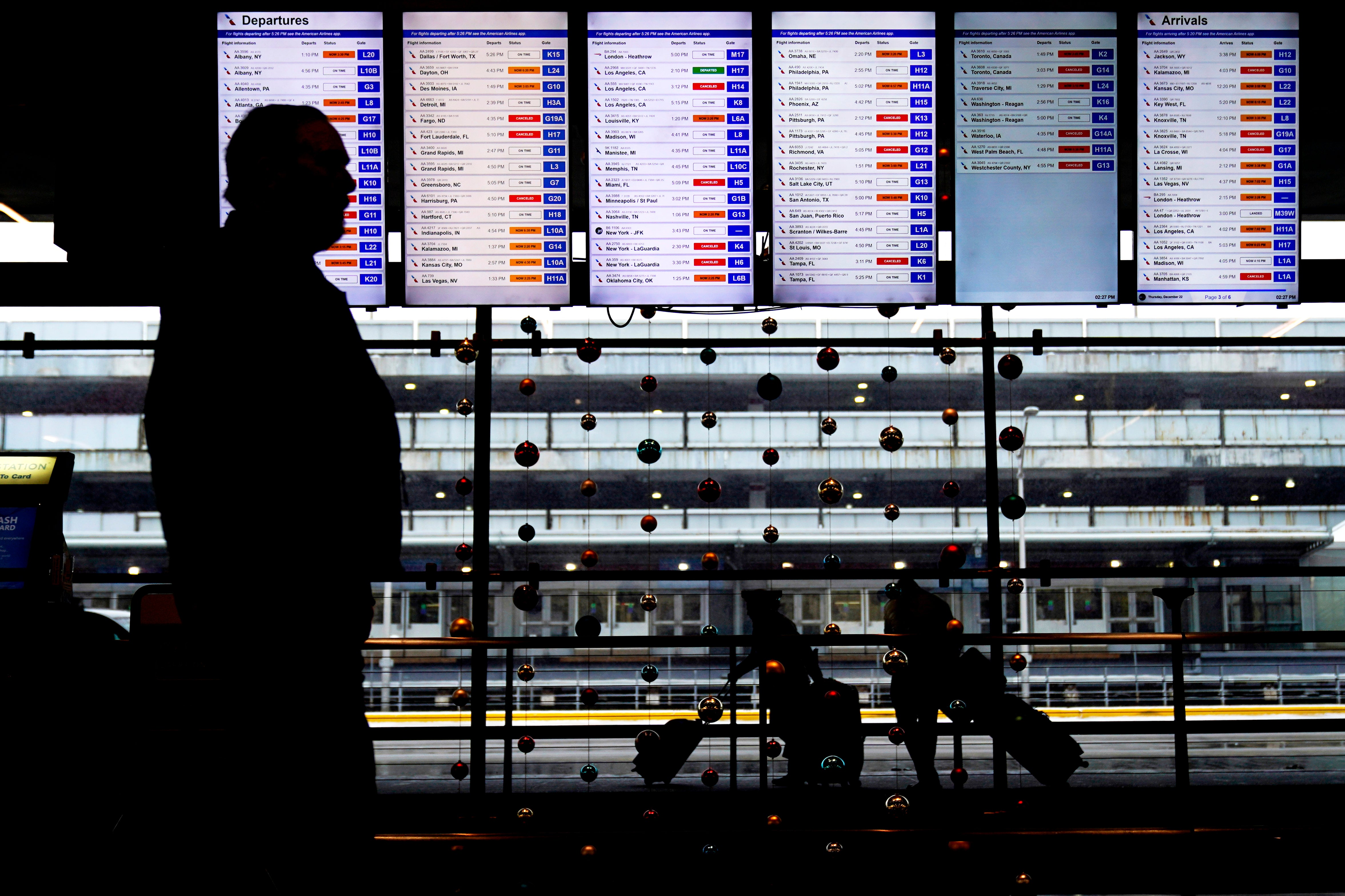 Travelers walk past flight information screens displaying flight status information at O'Hare International Airport in Chicago on Thursday