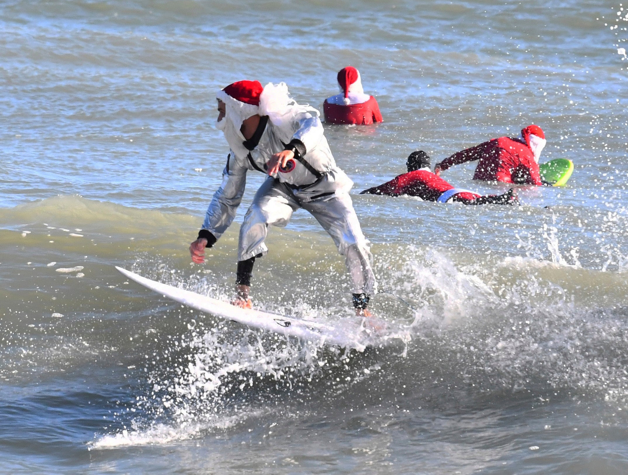 Surfer Corey Howell in a space man Surfing Santa suit, rides with waves with other surfing Santas for the 14th annual Surfing Santas of Cocoa Beach event Christmas Eve morning, Saturday, Dec. 24, 2022