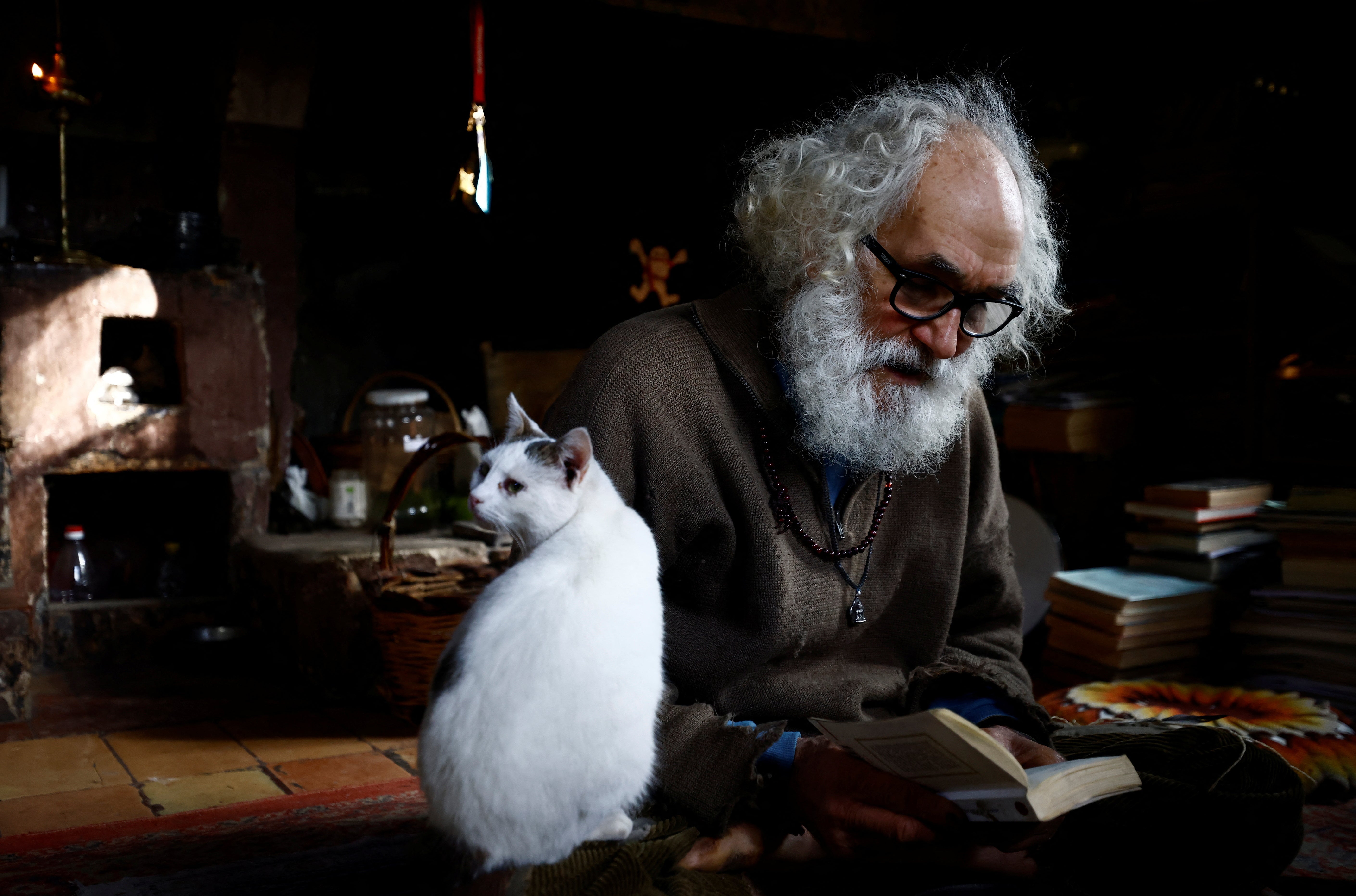 Fabrizio sits with his cat while reading a book