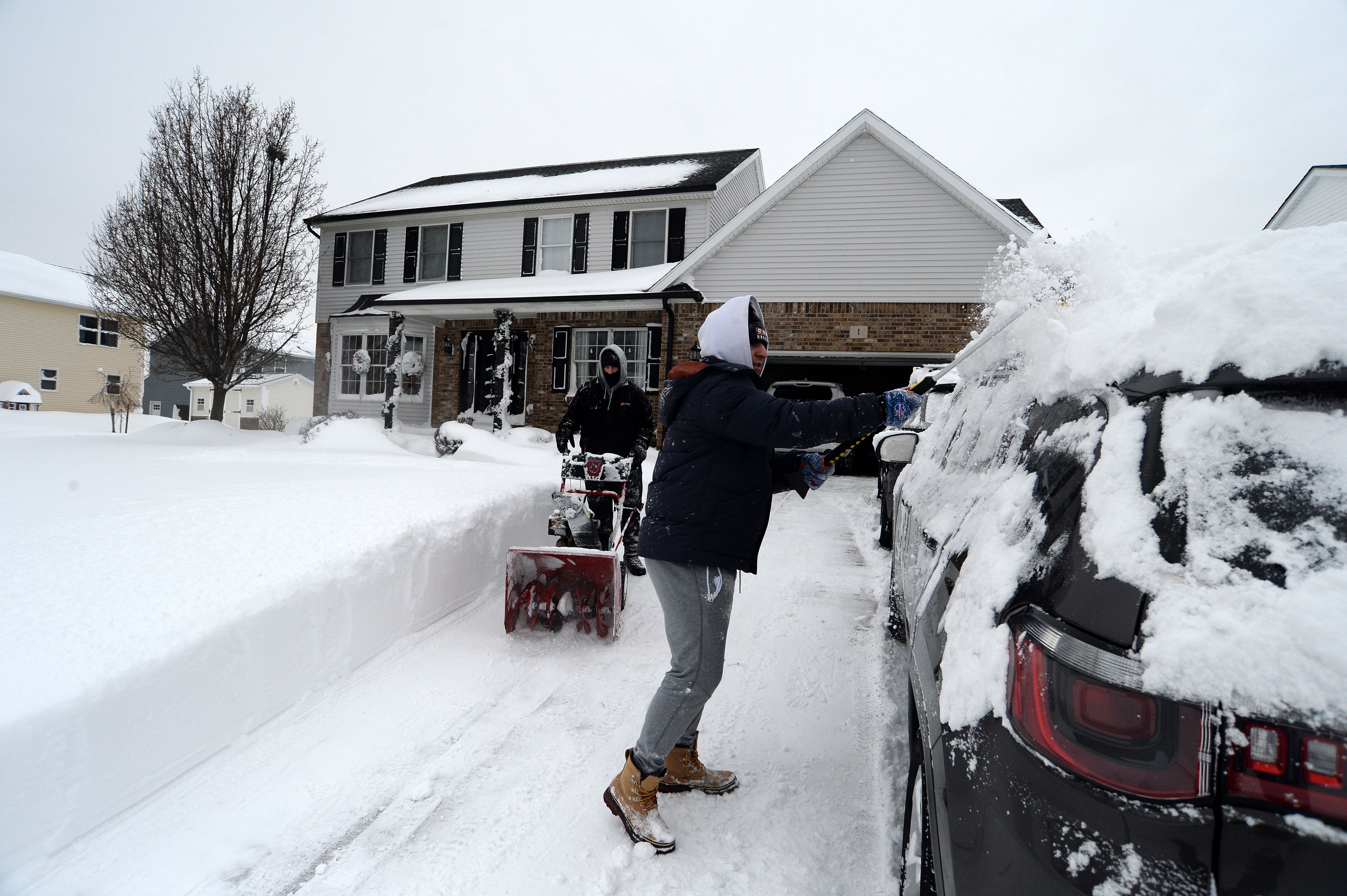 Jerry and Aidan Hughes clear snow from their home in West Seneca, New York