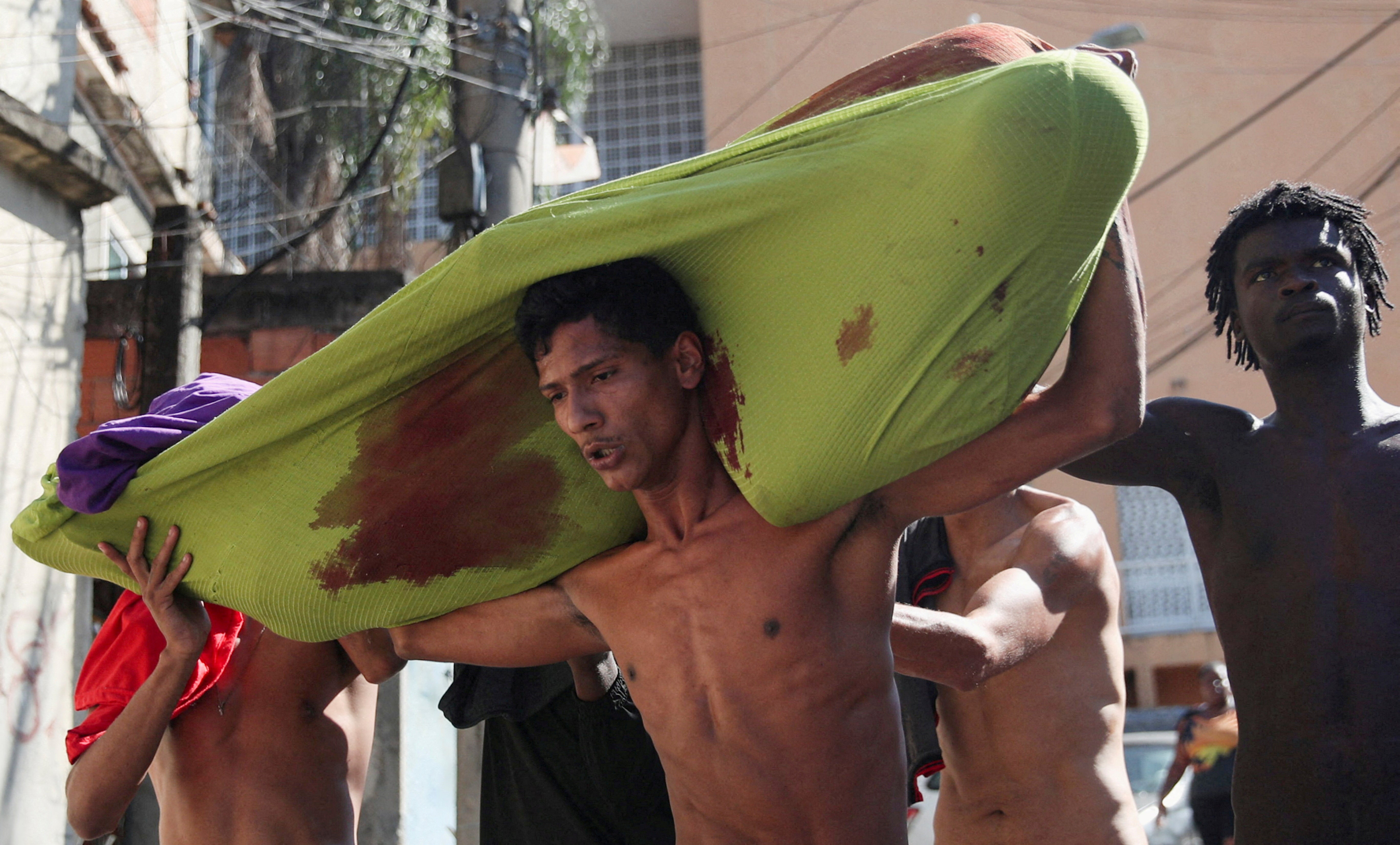 People carry a dead body during a police operation against drug gangs in the Alemao slums complex