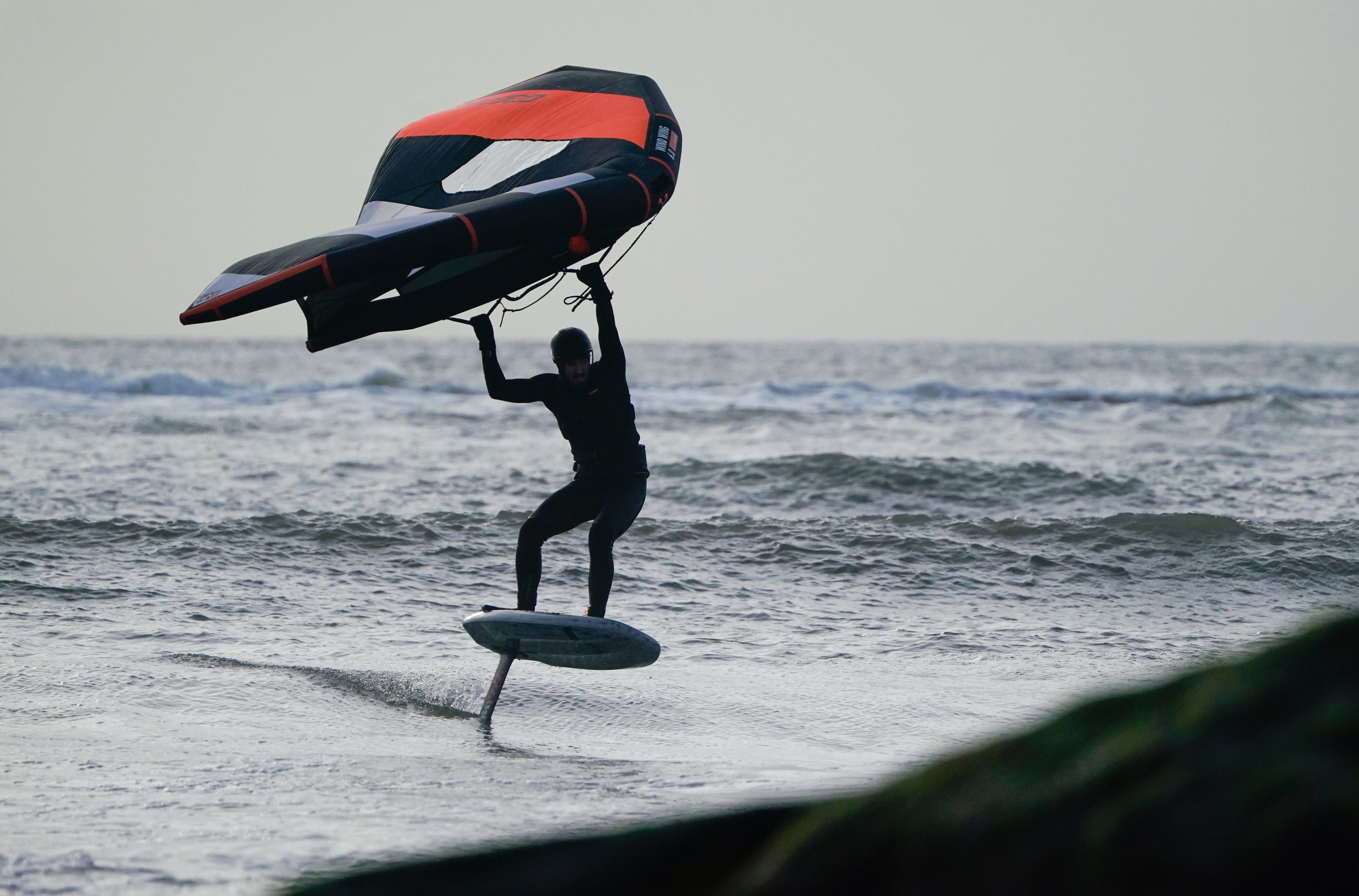 A person windsurfs in the sea off Avon beach in Mudeford, Dorset