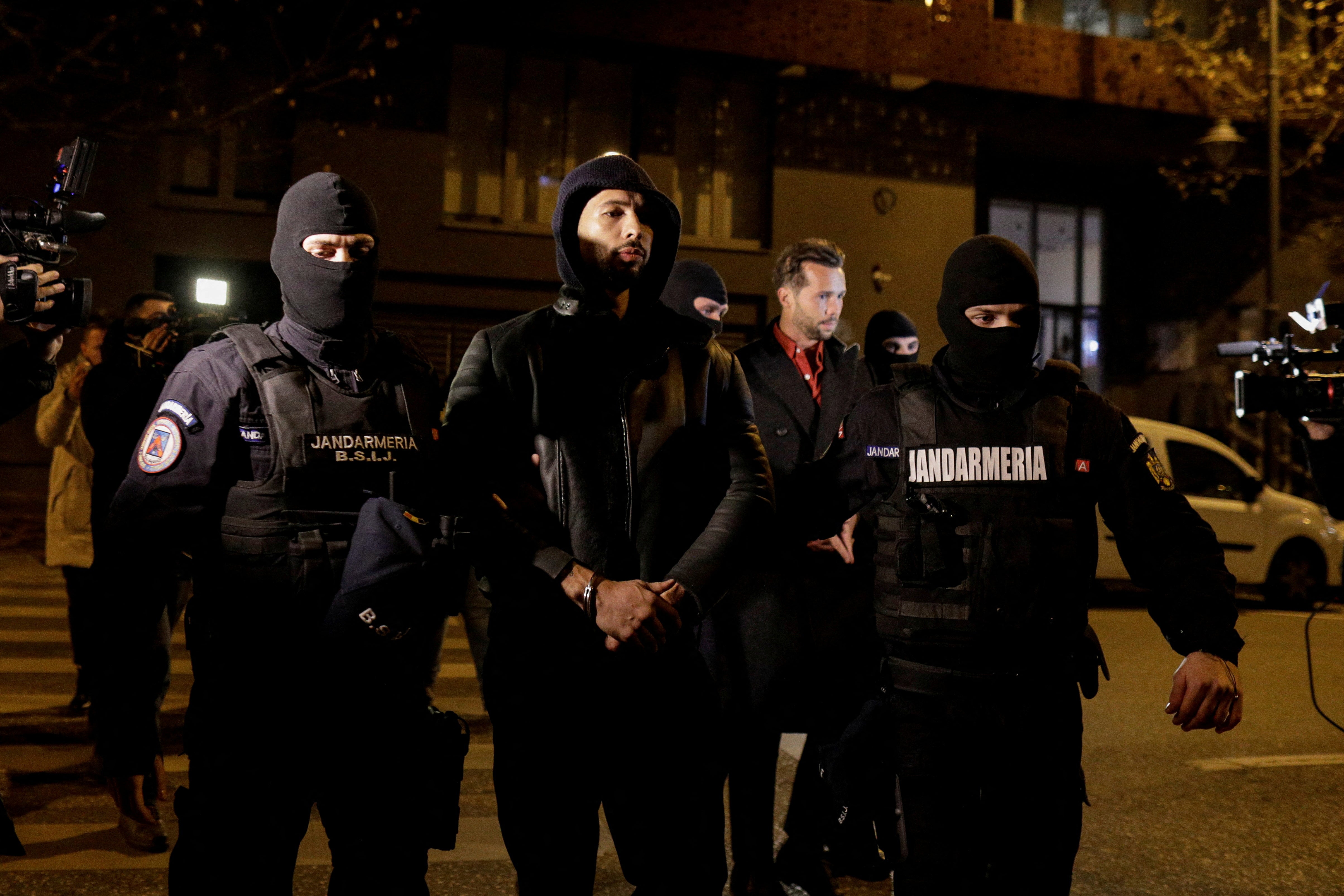 Andrew Tate and Tristan Tate are escorted by police officers outside the headquarters of the Directorate for Investigating Organized Crime