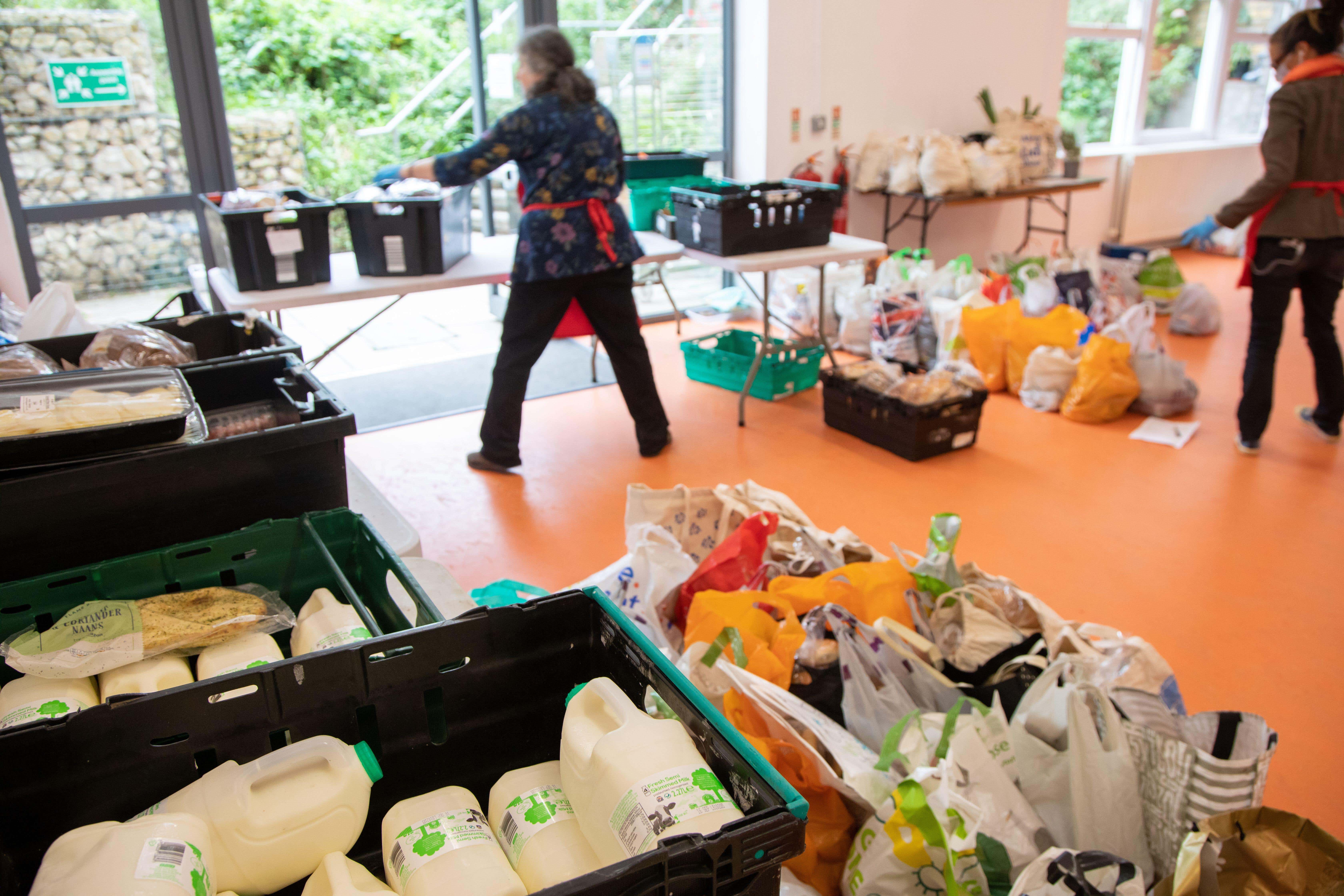 Two women volunteers at a food bank sorting crates of donated food in preparation for distributing to members of the local community in need. (Jonathan Goldberg / Alamy Stock Photo)