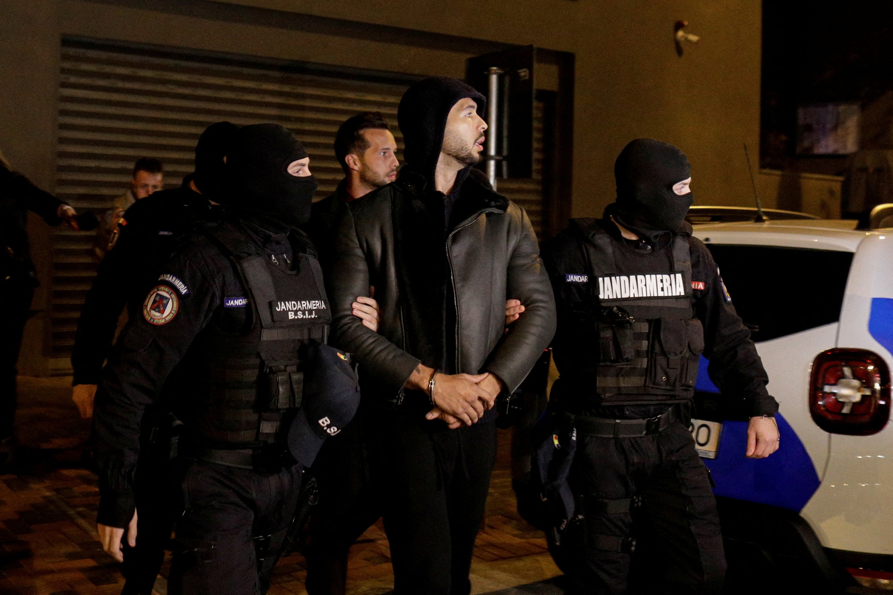 Andrew Tate and Tristan Tate are escorted by police officers outside the headquarters of the Directorate for Investigating Organized Crime and Terrorism in Bucharest (DIICOT) after being detained for 24 hours
