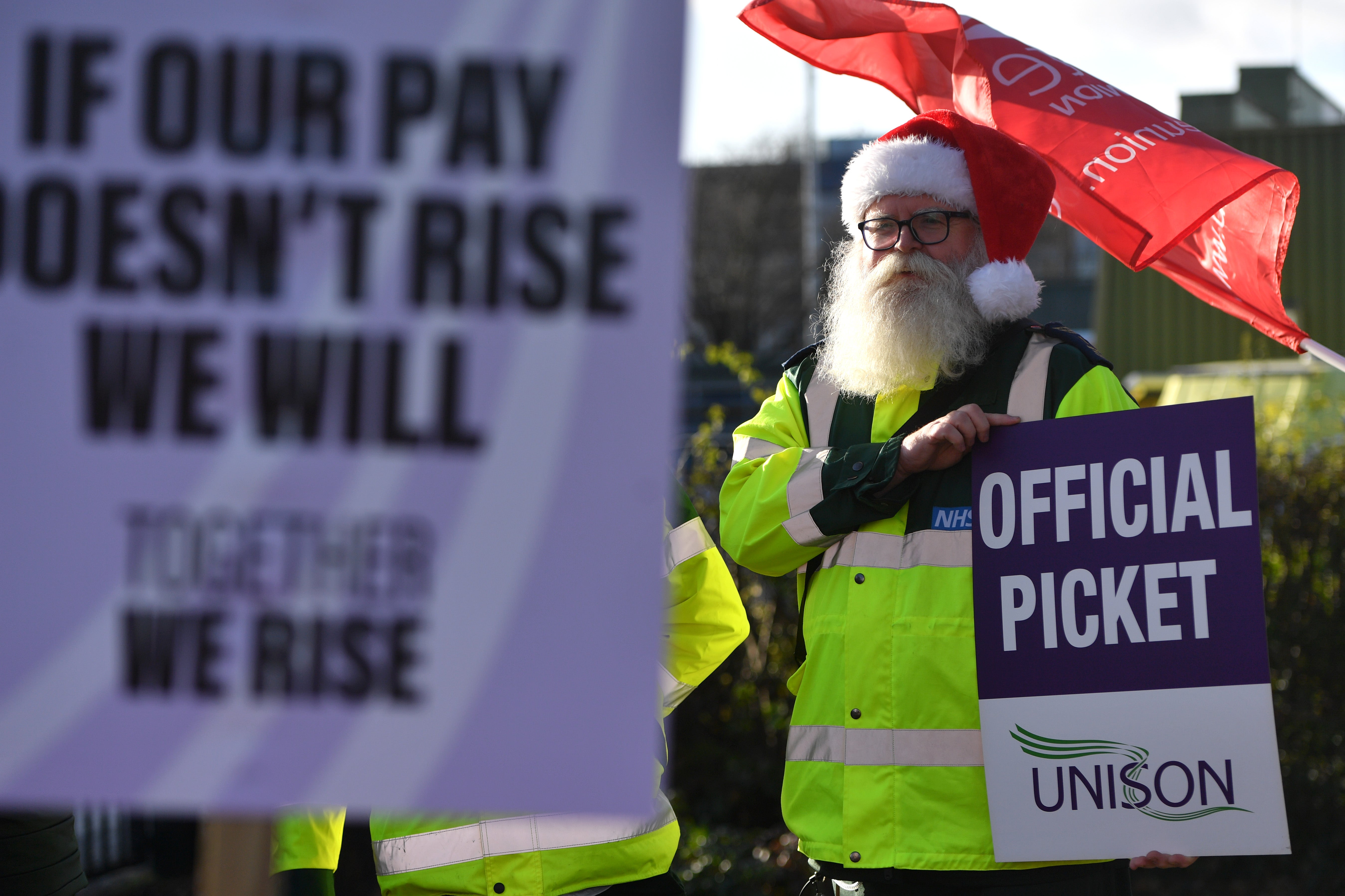 A demonstrator holds a placard on a picket line at a Manchester ambulance station