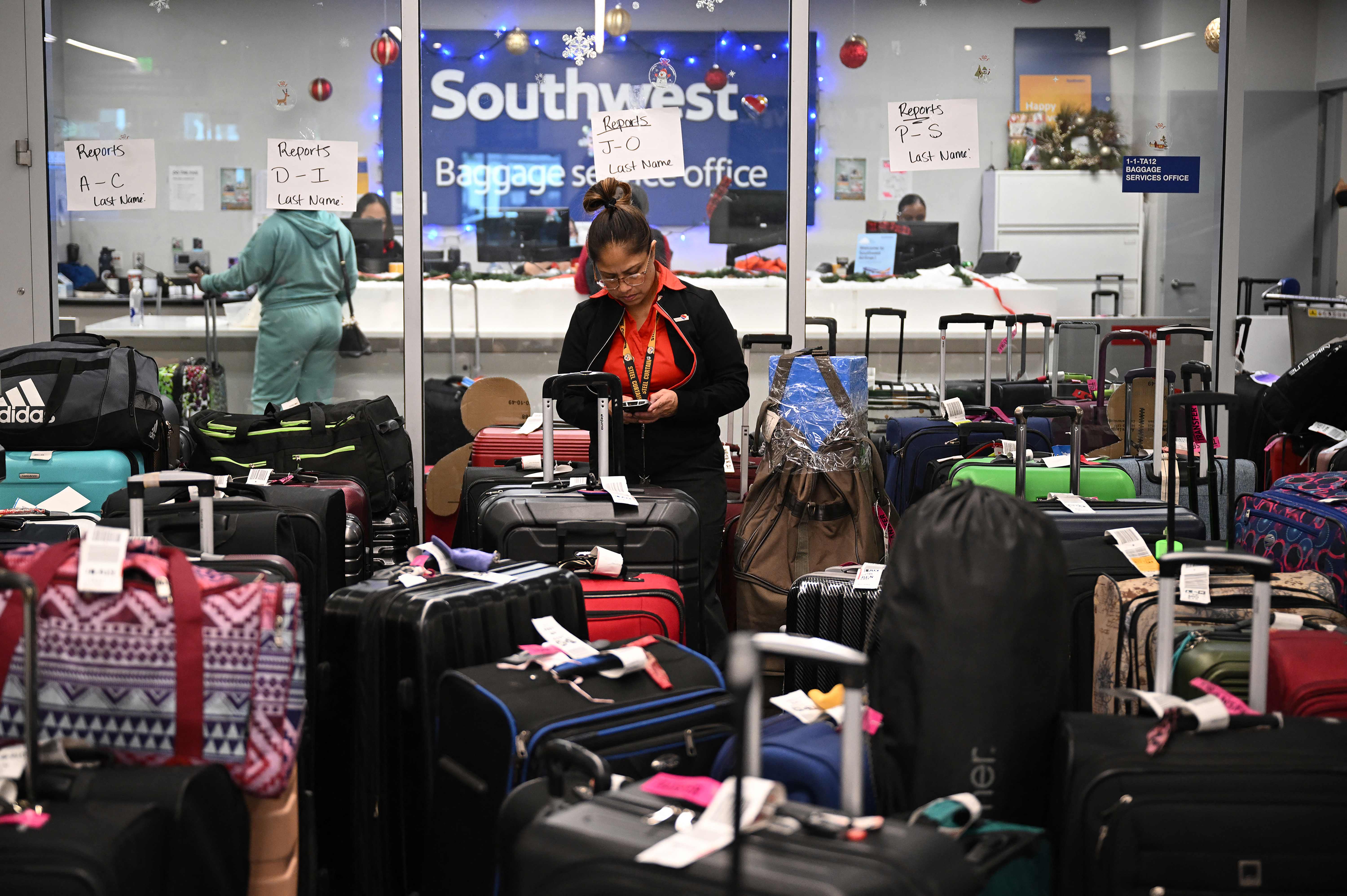 A ground crew member organises unclaimed luggage at LA airport during a storm which caused the cancellations of thousands of flights across the US