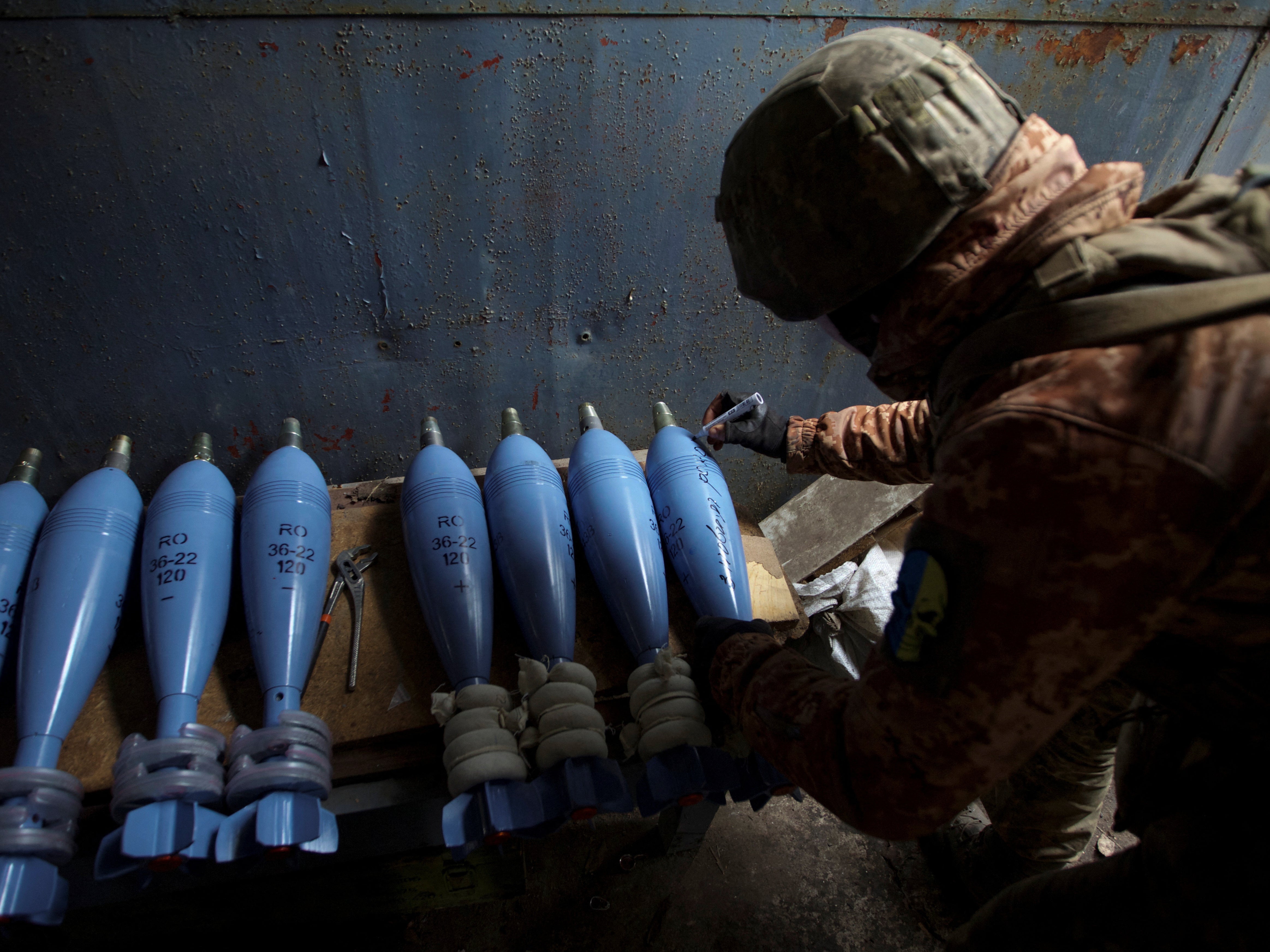 A Ukrainian serviceman writes an inscription reading ‘Happy New Year’ on a mortar shell before firing towards positions of Russian troops