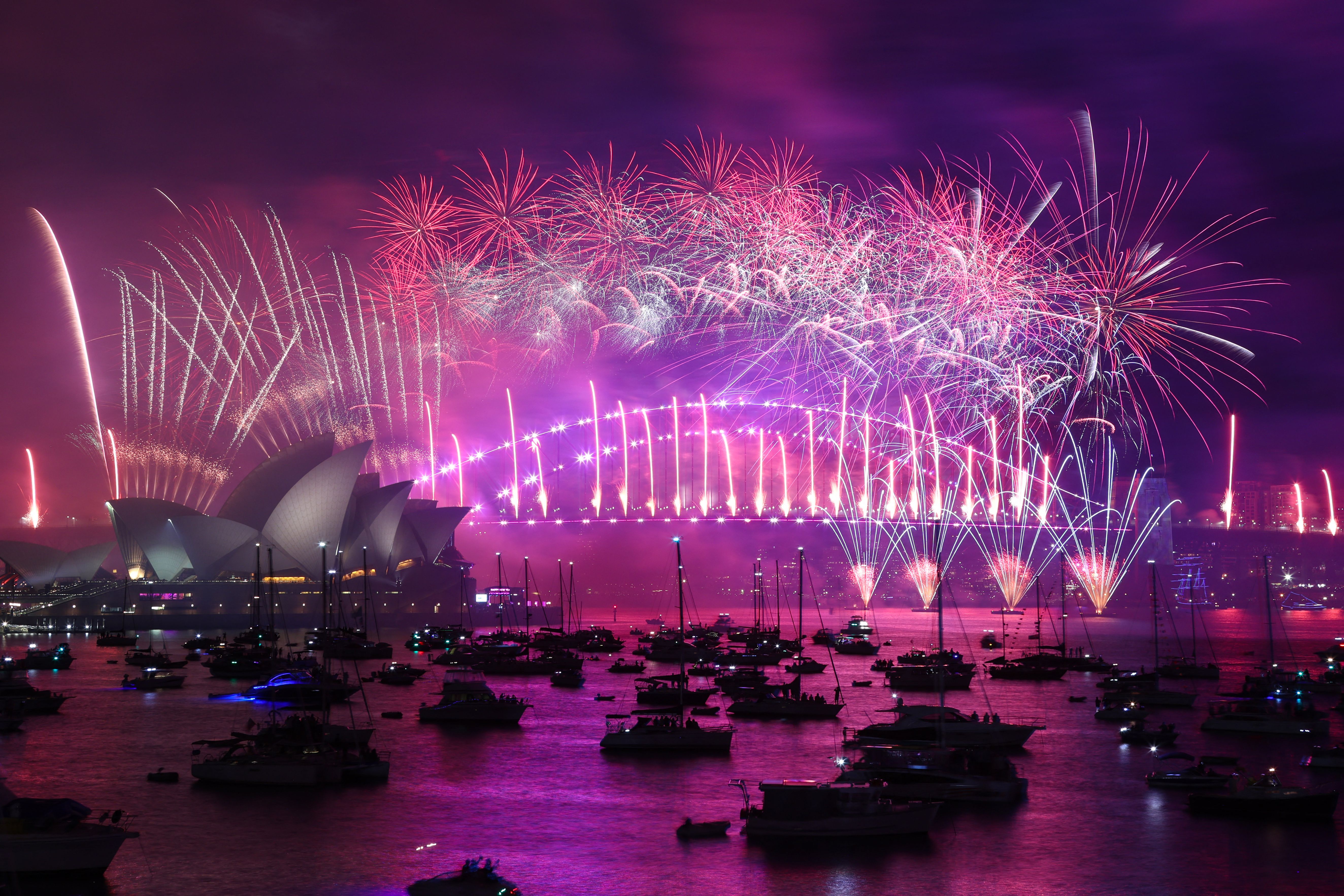 New Year's Eve fireworks light up the sky over the Sydney Opera House (L) and Harbour Bridge