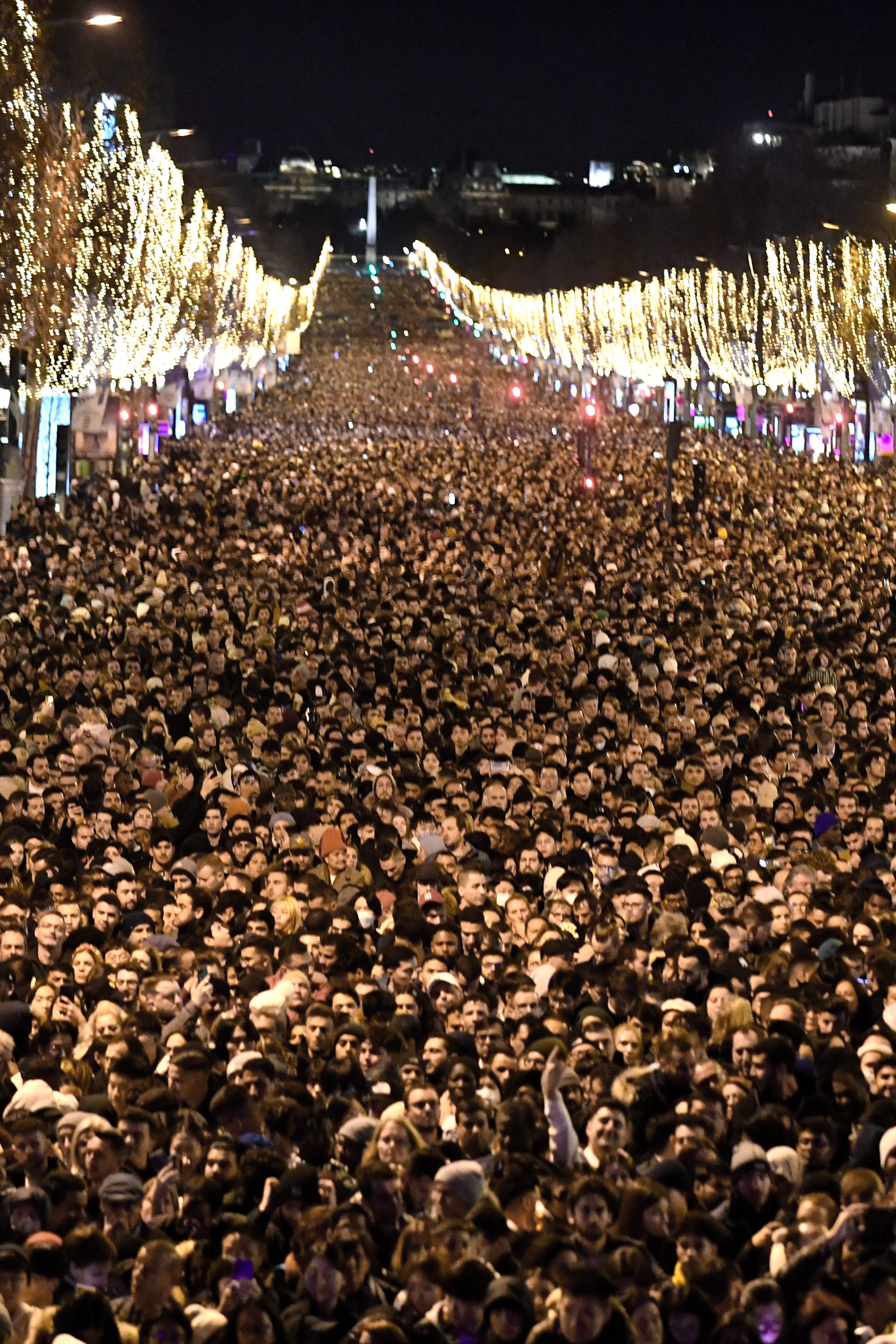 People gather on the Champs-Elysee as they wait for the New Year's Eve fireworks in Paris