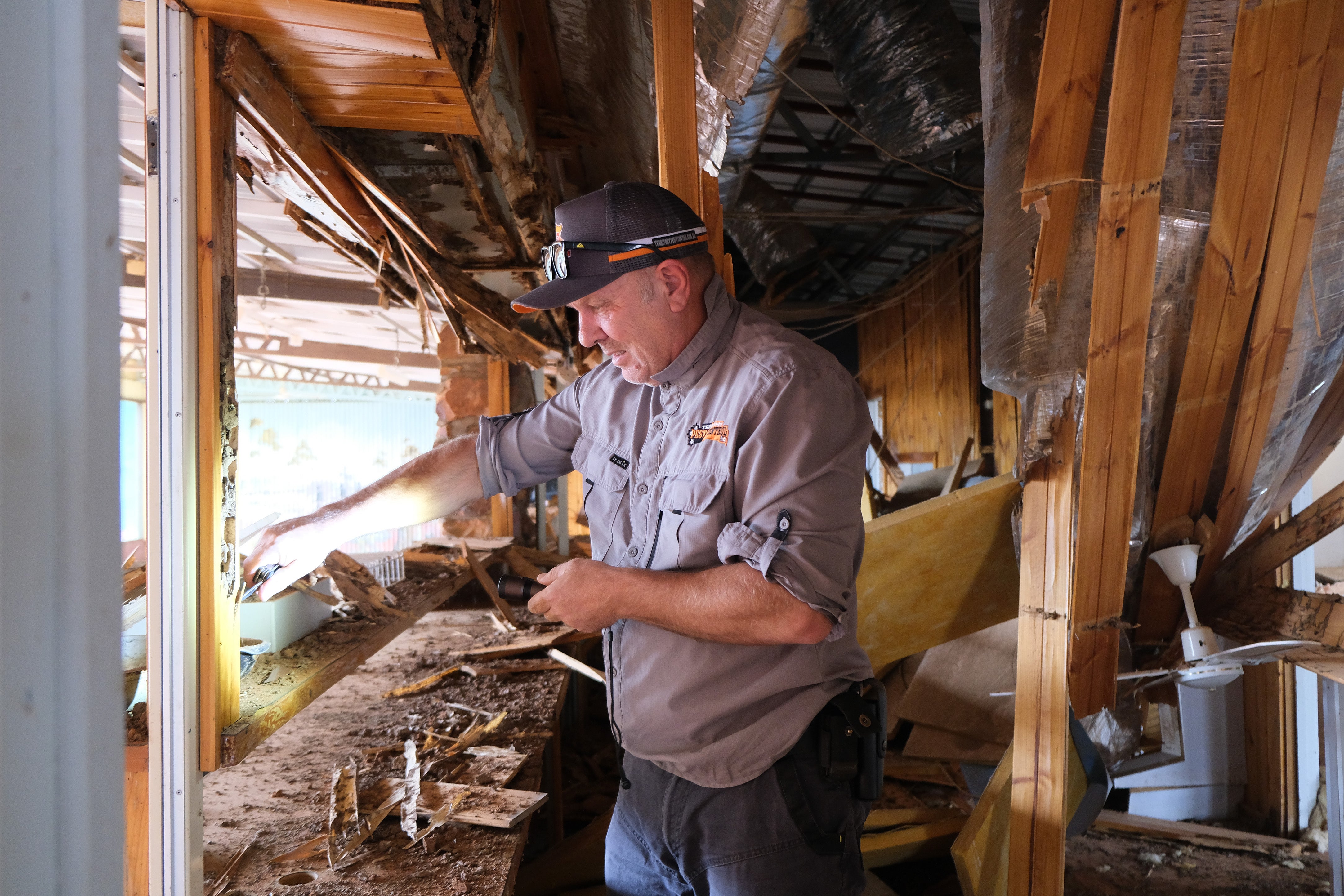 Cook peels back the remaining wood on a door frame at the restaurant