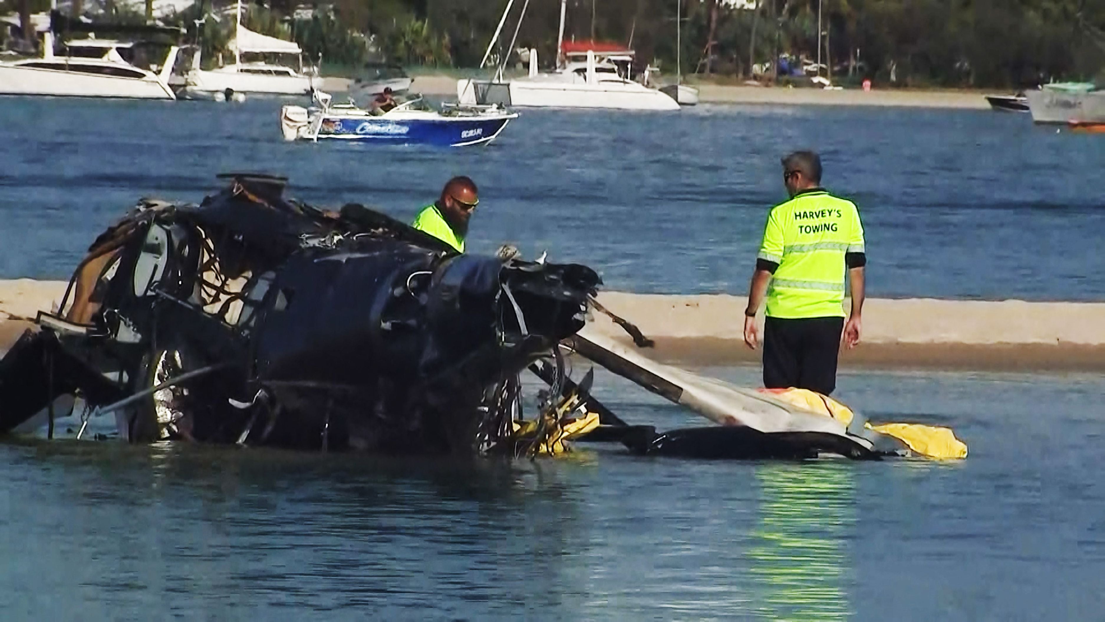Airport workers prepare to remove a crashed helicopter that collided with another helicopter on the Gold Coast