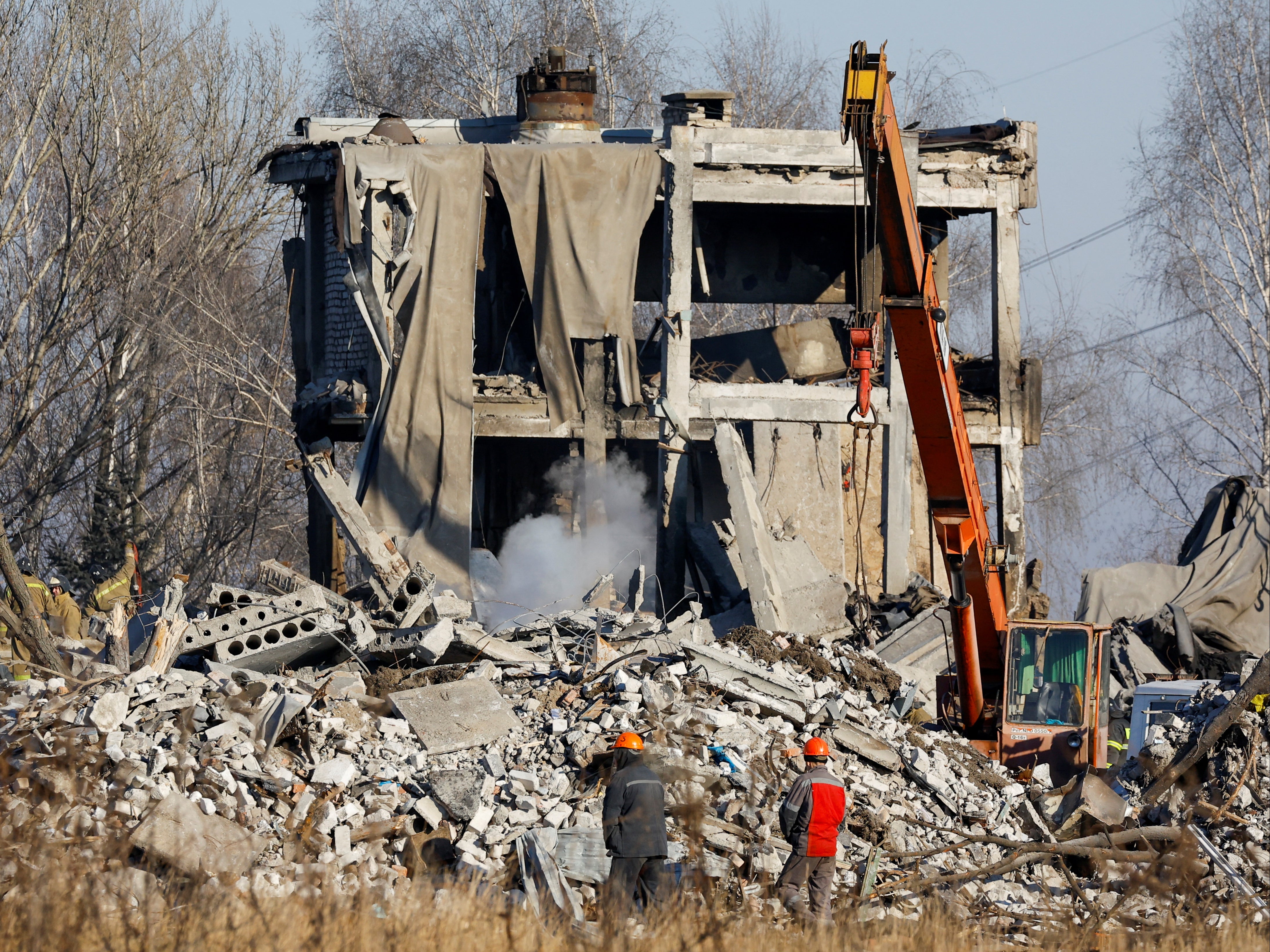 Workers remove debris of a destroyed building in Makiiva reported to have been used as a temporary barracks by Russian troops before a Ukrainian strike