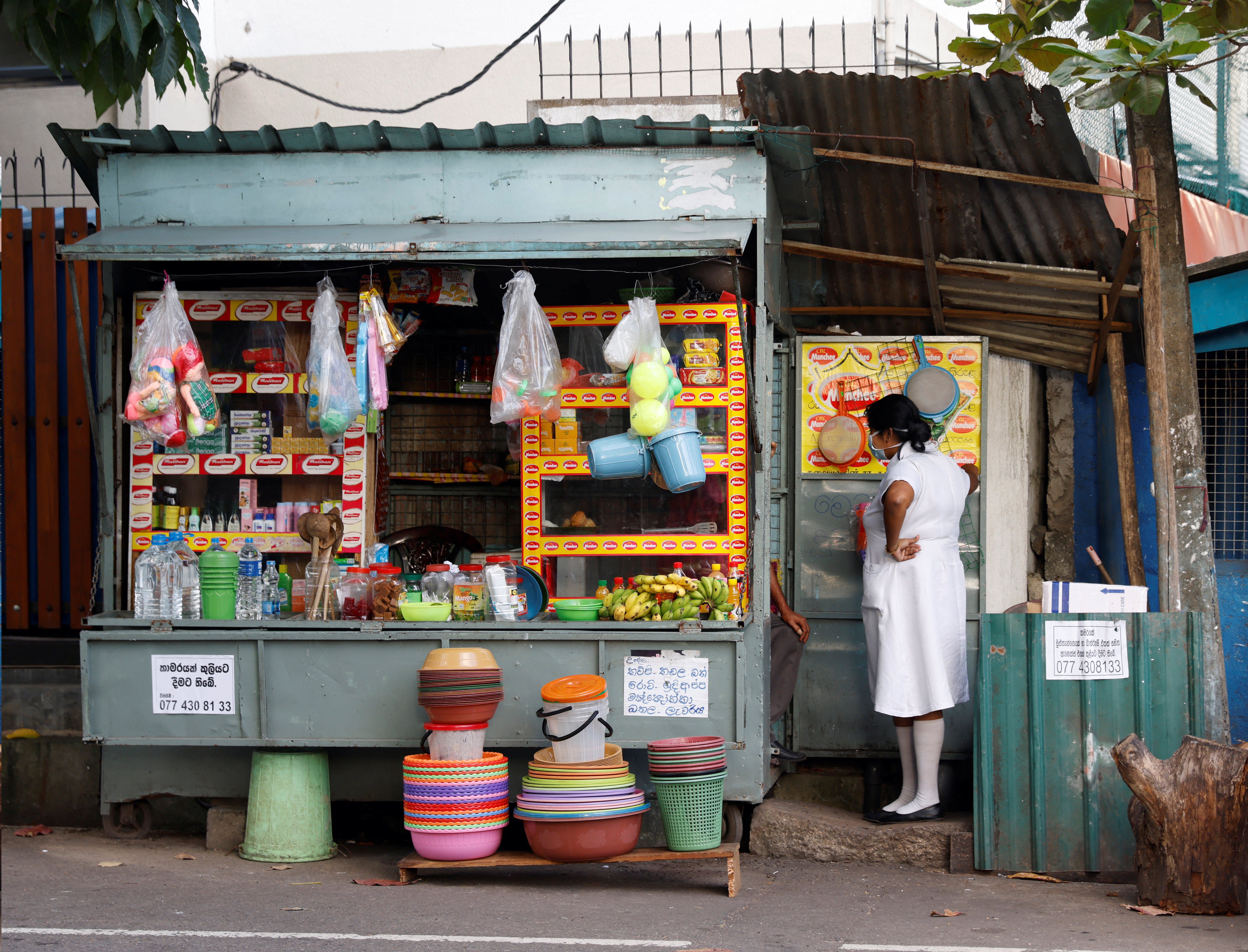 A medical worker talks to a vendor selling household goods and food for patients and their family members outside Apeksha Hospital