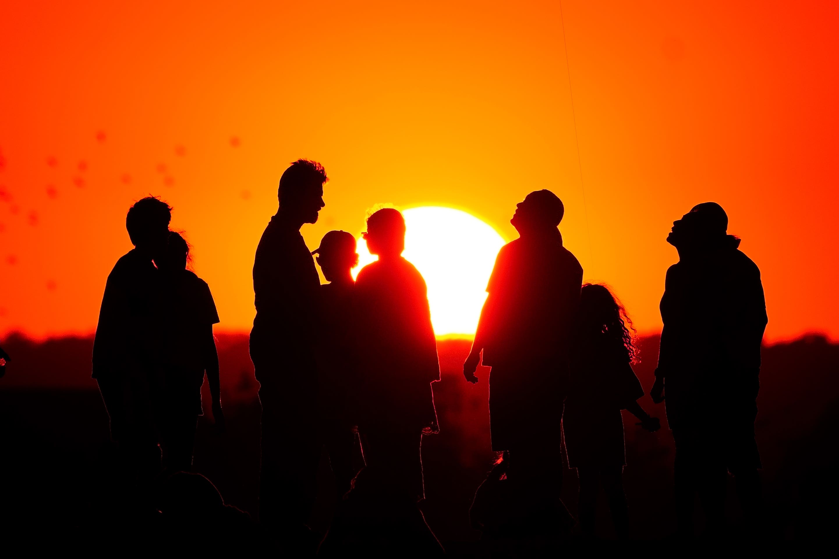 A crowd of people watch the setting sun from a hill in Ealing, west London (Victoria Jones/PA)