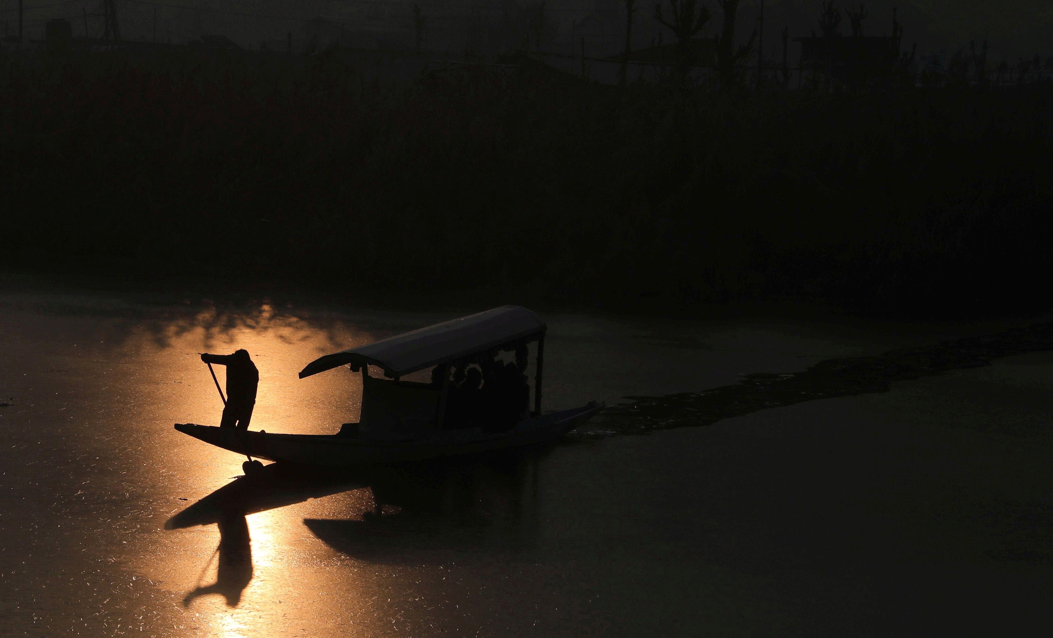 A Kashmiri boatman makes his way through partially frozen surface on the waters of Dal Lake as sun rises on a cold morning in Srinagar