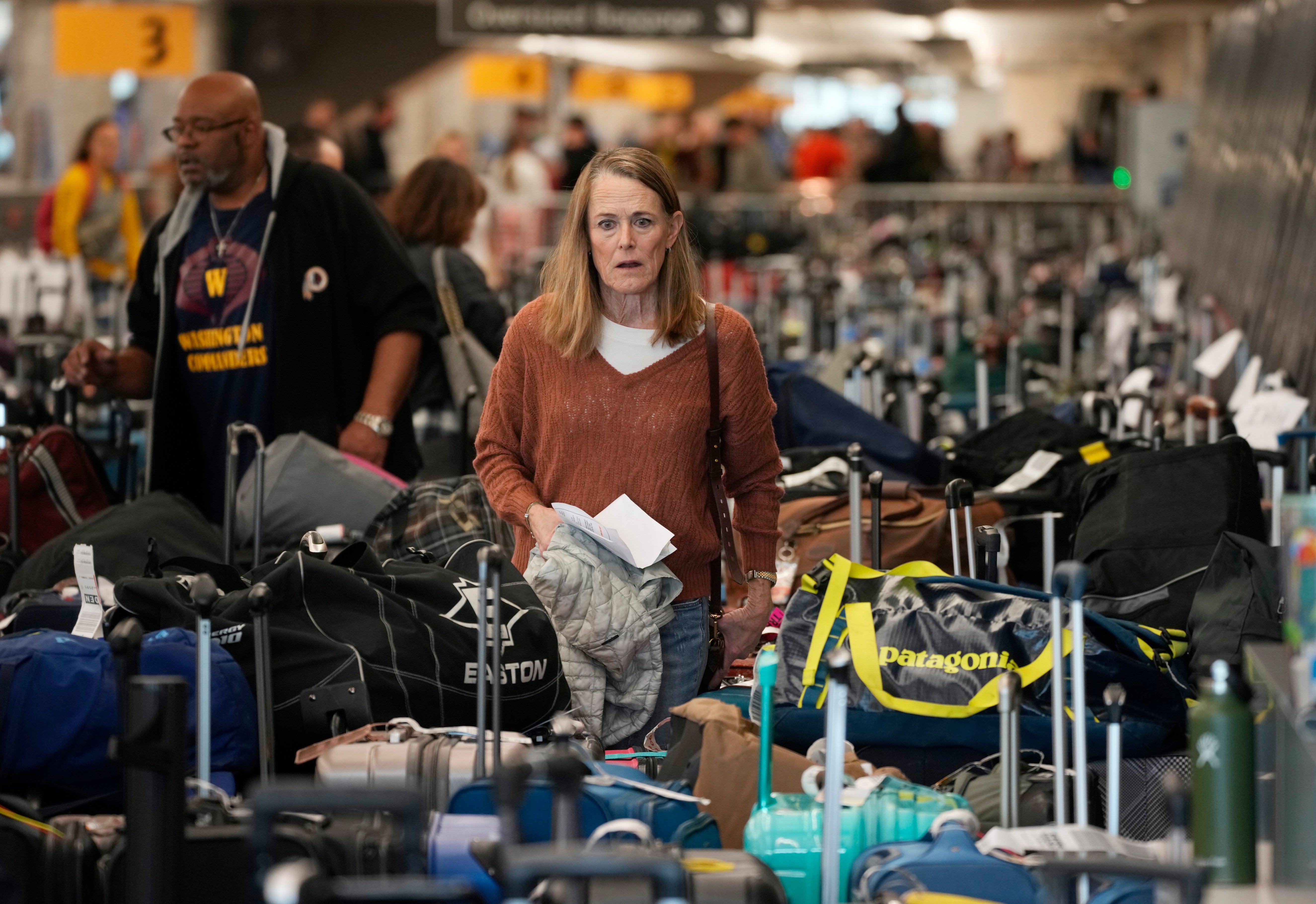 A passenger wades through a mountain of luggage amid thousands of Southwest Airlines cancellations