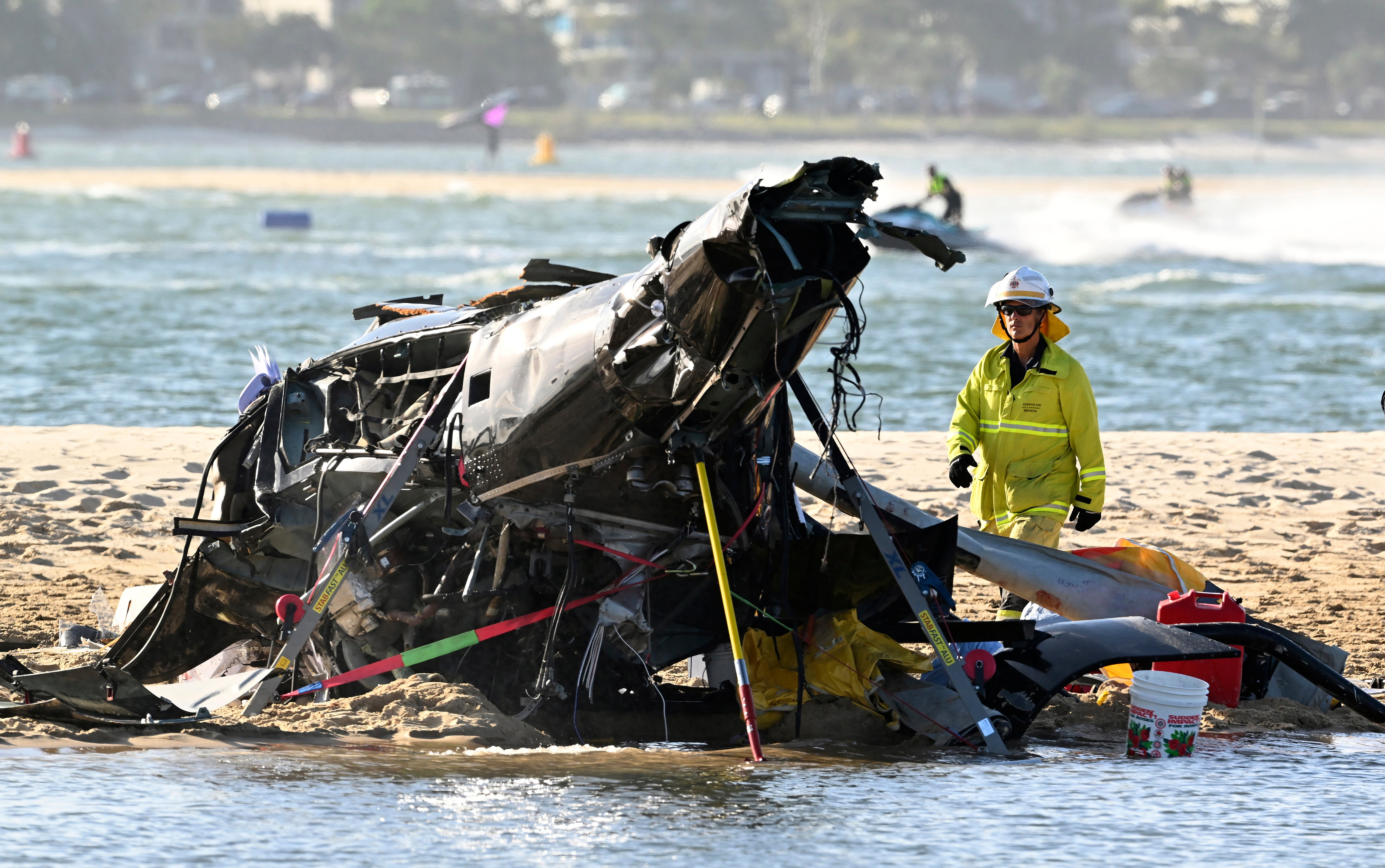 An emergency worker looks over a crashed helicopter following a collision near SeaWorld, on the Gold Coast, Australia