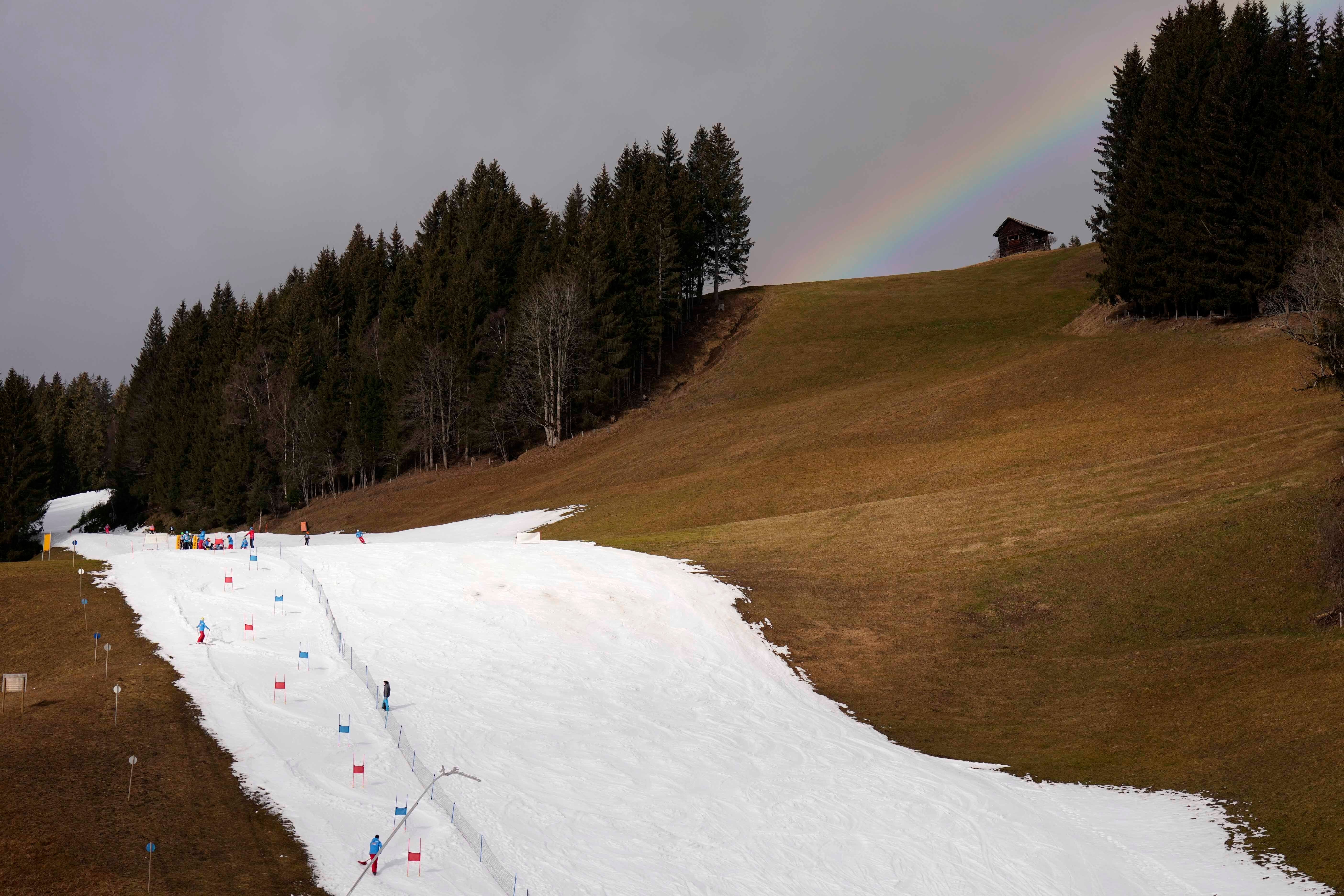 People skiing on a slope in Filzmoos south of Salzburg, Austria, Thursday, January 5, 2023. Sparse snowfall and unseasonably warm weather in much of Europe is allowing green grass to blanket many mountaintops