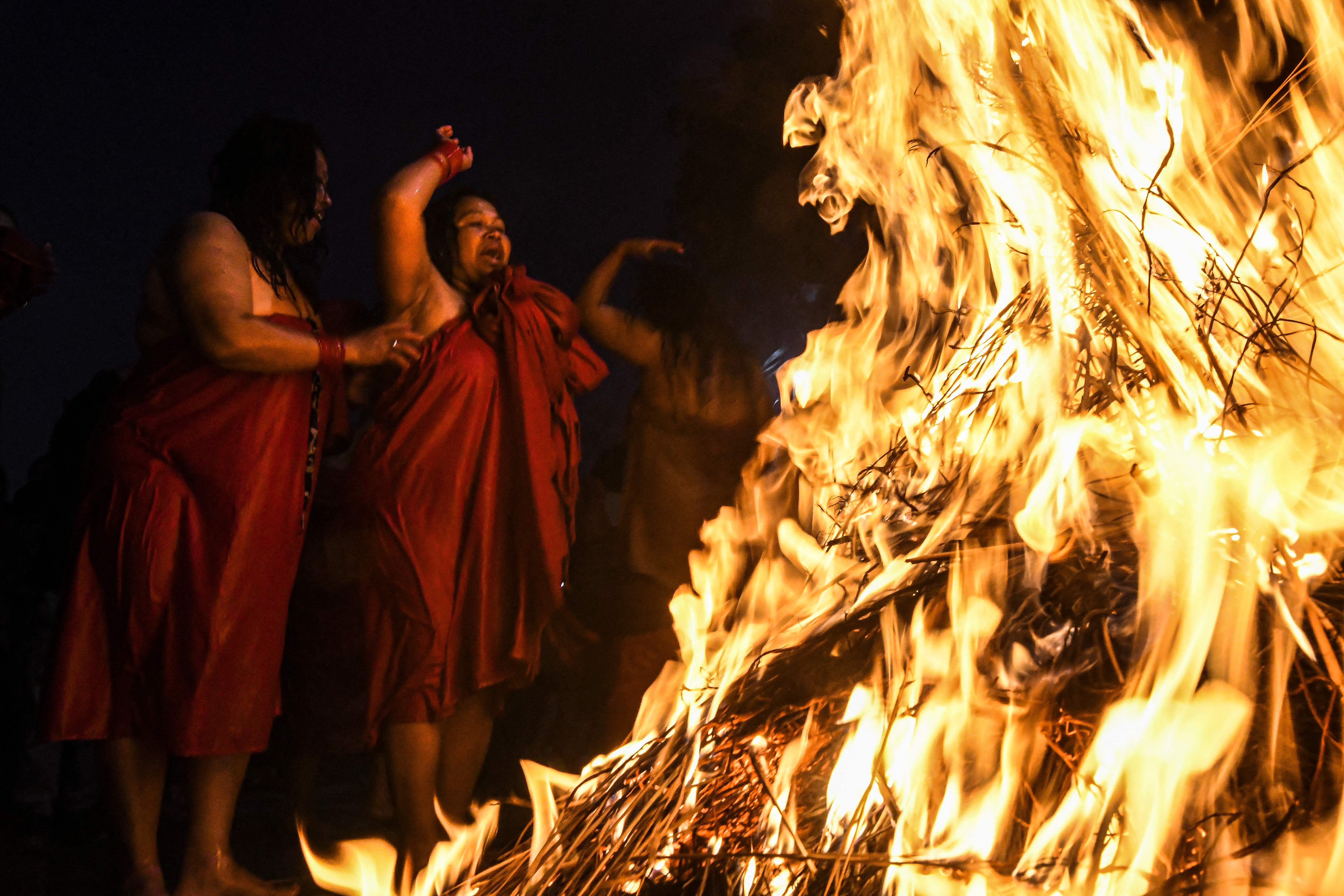 Hindu devotees warm themselves around bonfires after bathing in the Shali river during the Swasthani Brata Katha festival