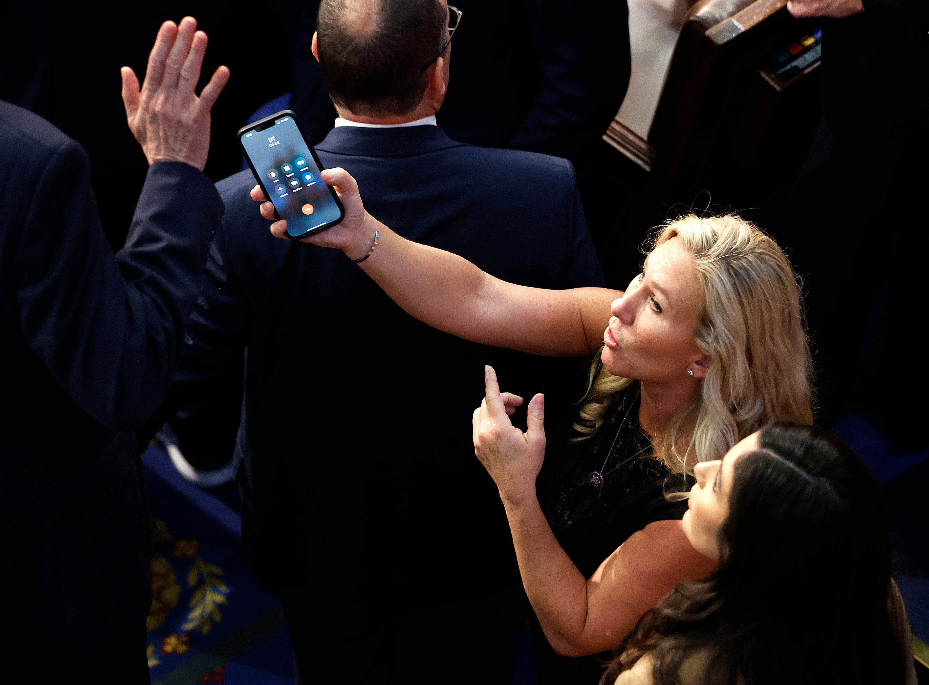 Marjorie Taylor Greene appears to show fellow Republican Matt Rosendale that Donald Trump is on the phone.