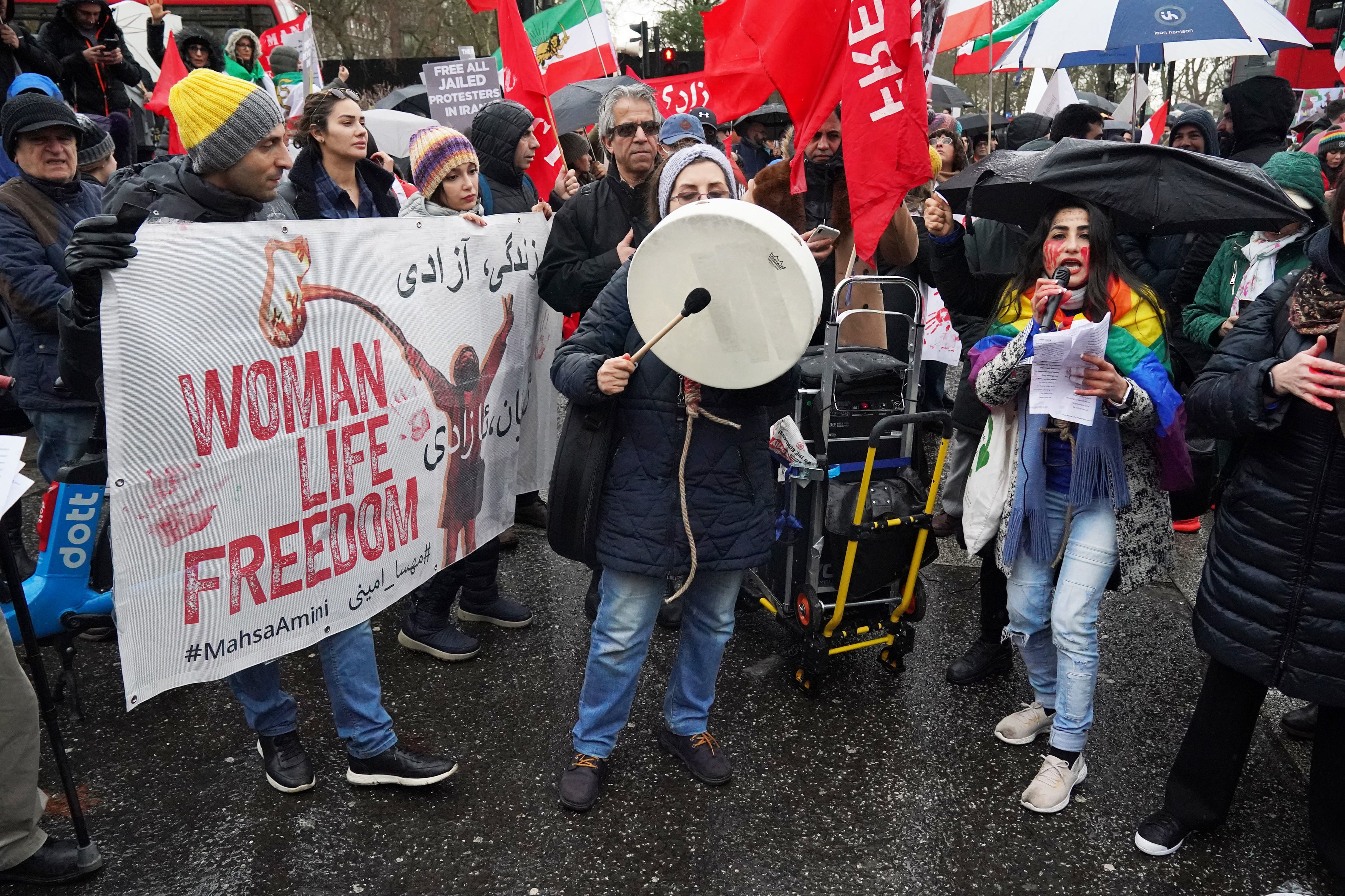 Protestors brandish banners emblazoned with the slogan “Woman, Life, Freedom”