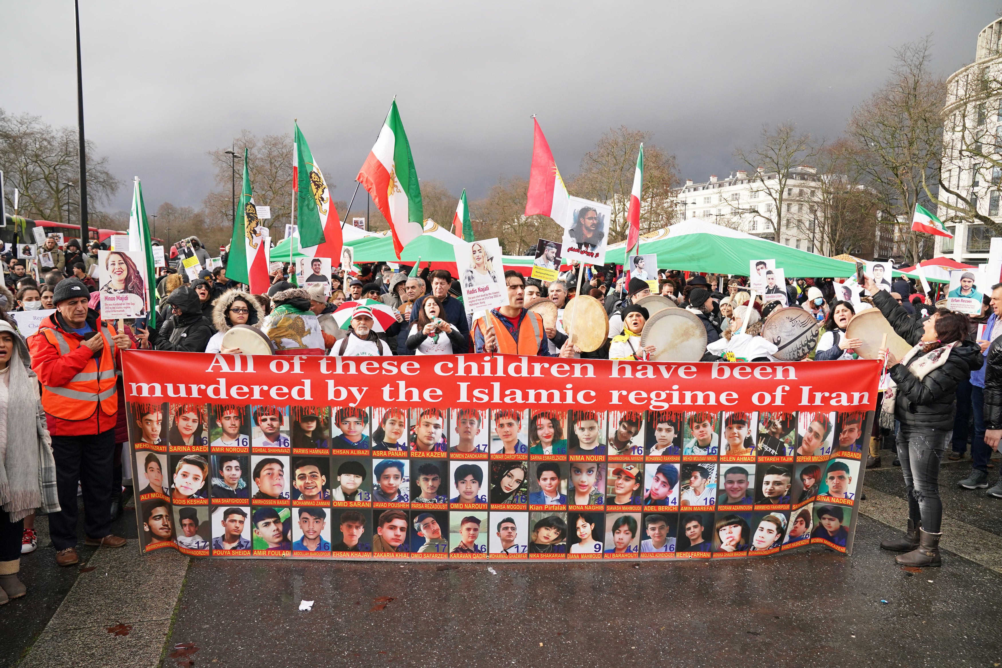 Protestors hold banners pasted with the faces of children allegedly killed by Iranian regime