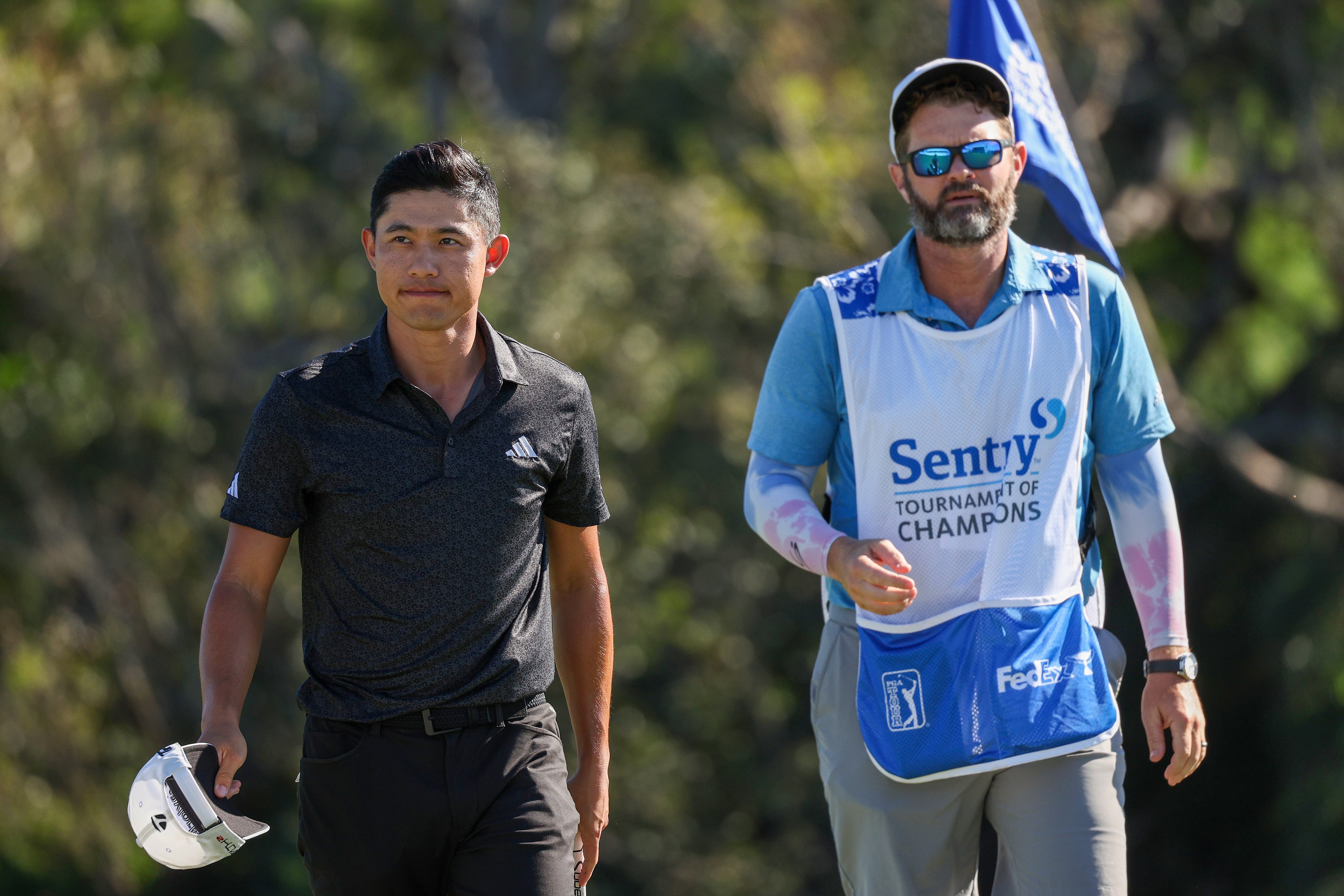 Collin Morikawa of the United States and caddie Jonathan Jakovac walk off the 18th green