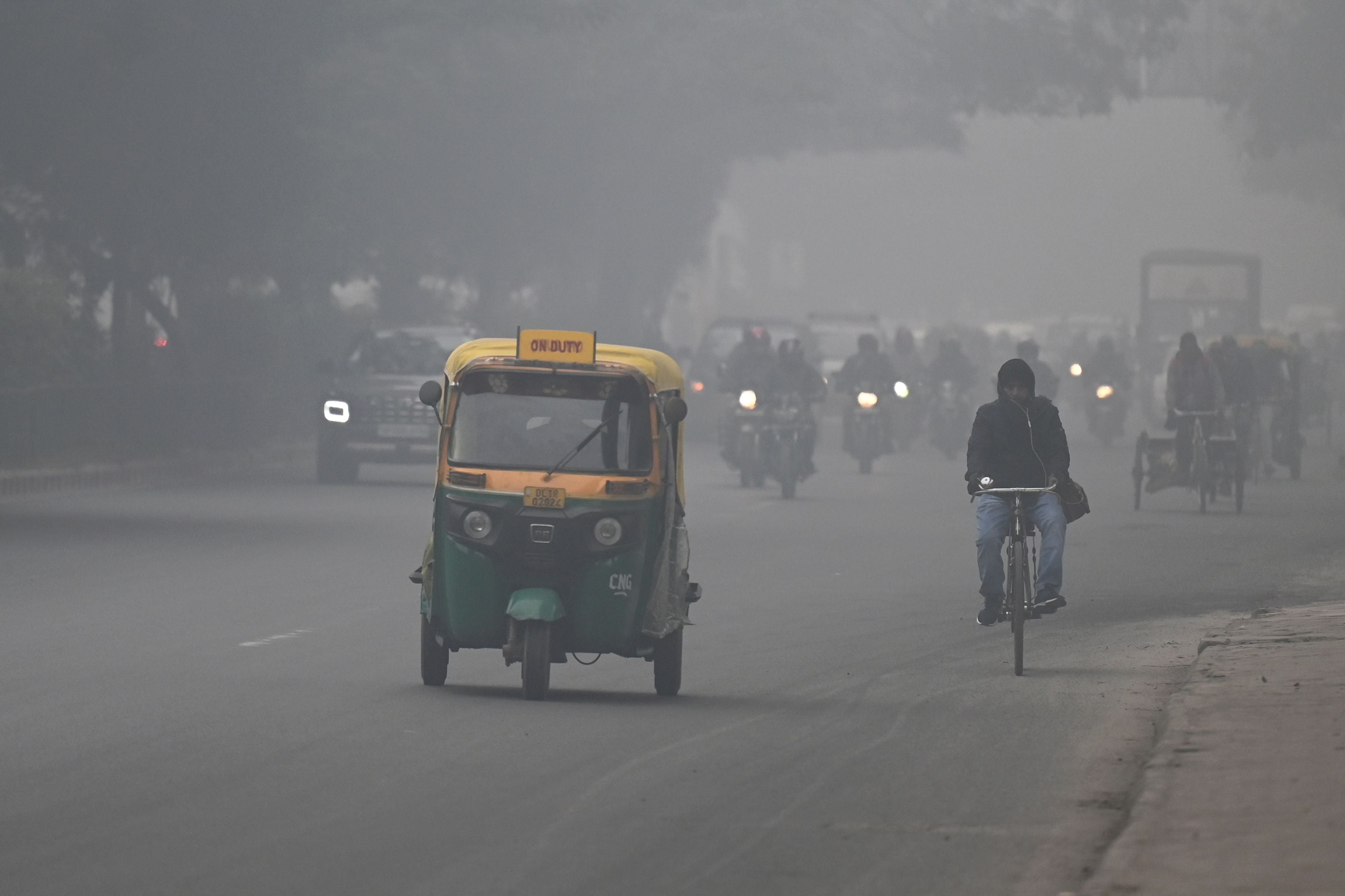 Commuters make their way along a street on a foggy winter morning in New Delhi on January 9, 2023.