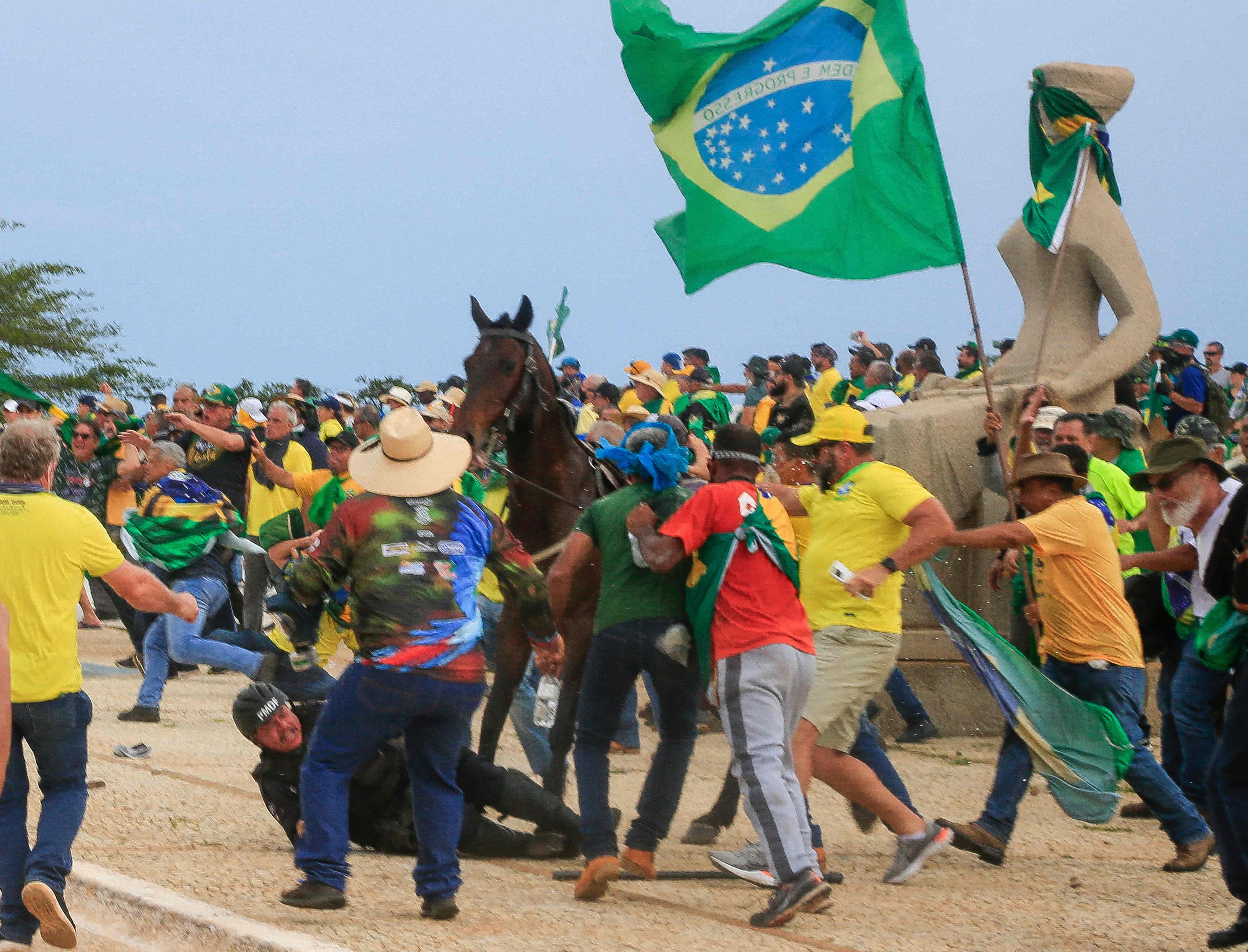 A military police officer falls from his horse during clashes with Bolsonaro supporters on Sunday