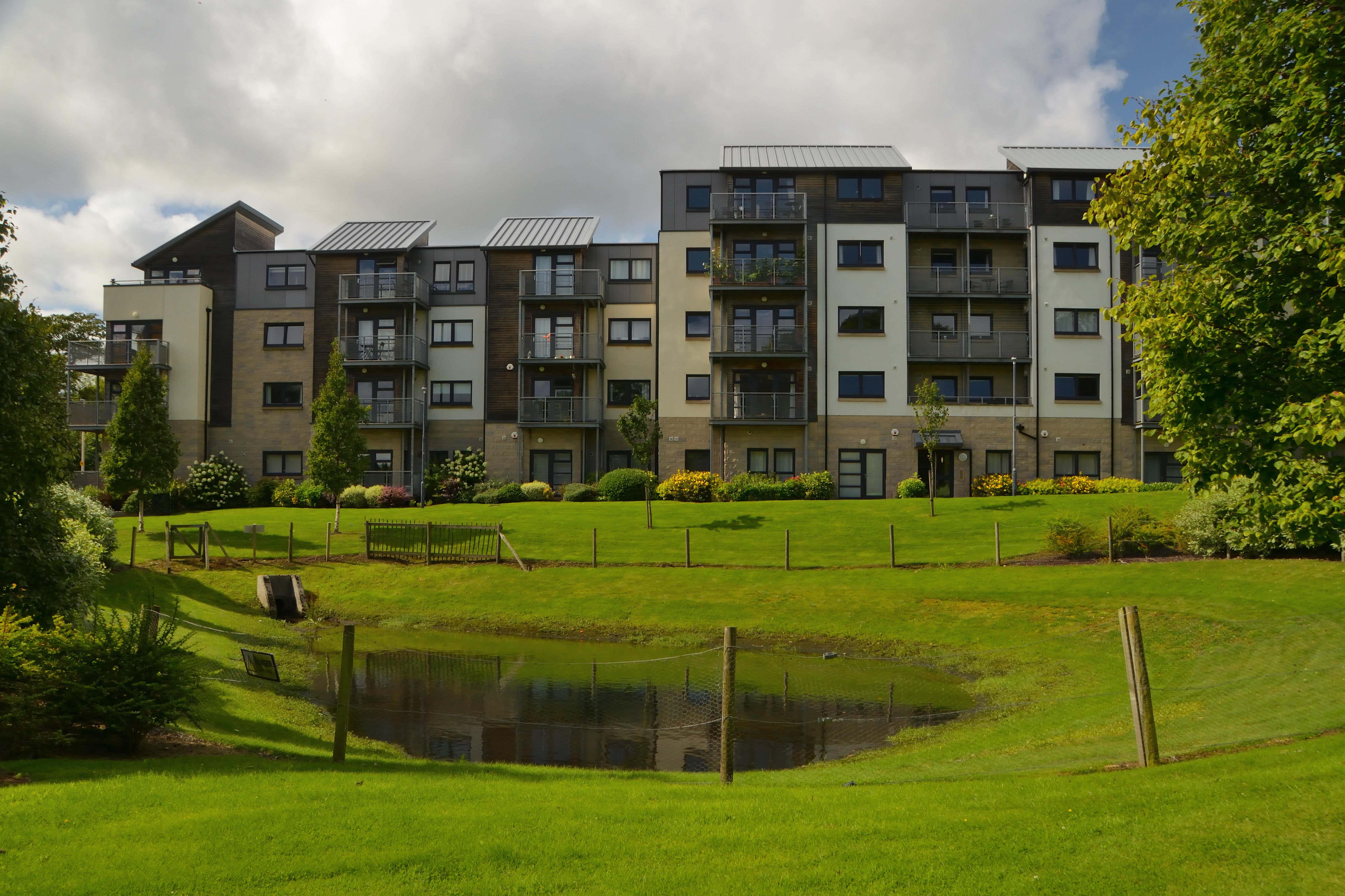 An apartment block with green landscaping and a balancing pond for sustainable drainage in Aberdeen (Alamy/PA)