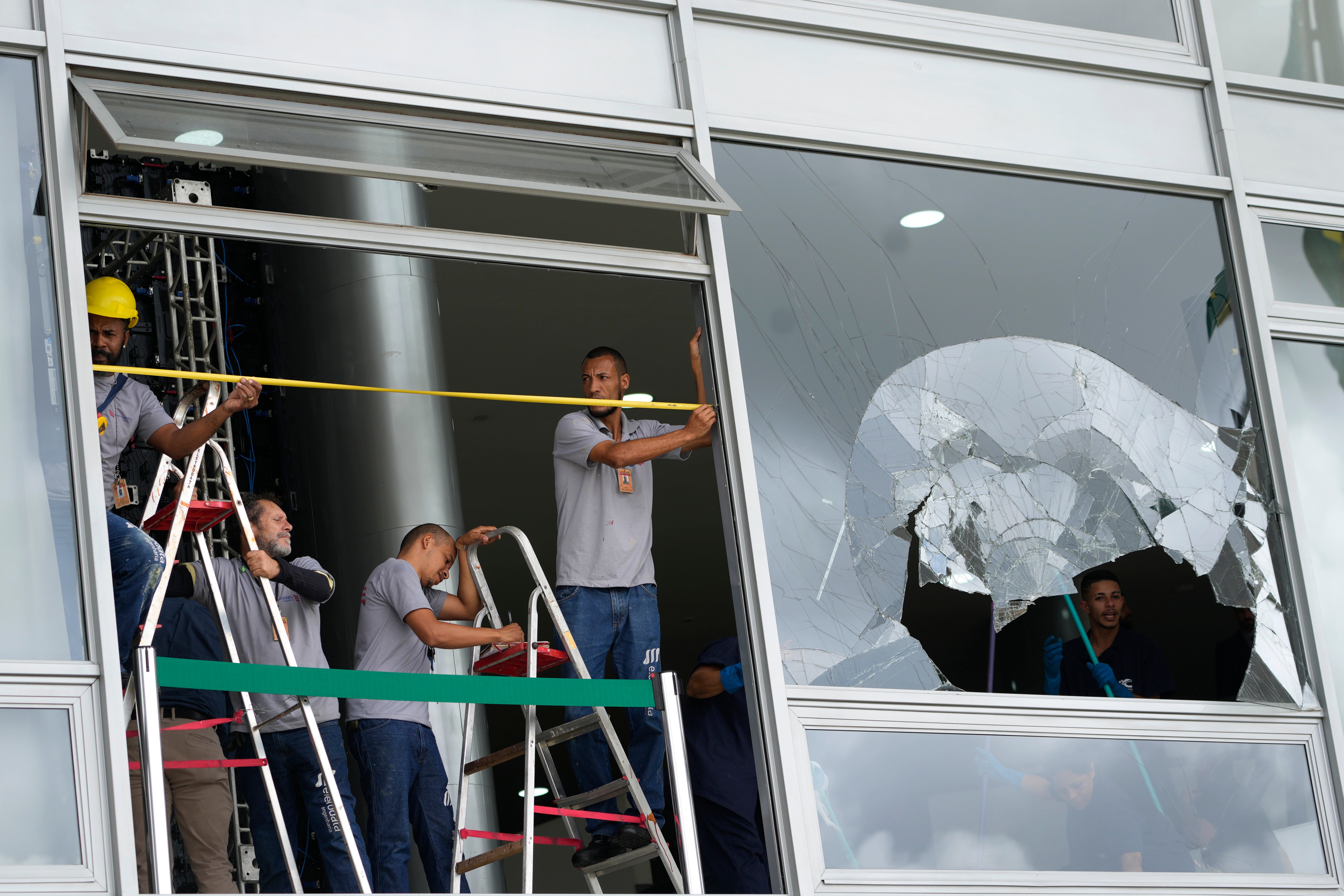 Wrokers measure the windows of Planalto Palace, the office of the president, the day after it was stormed