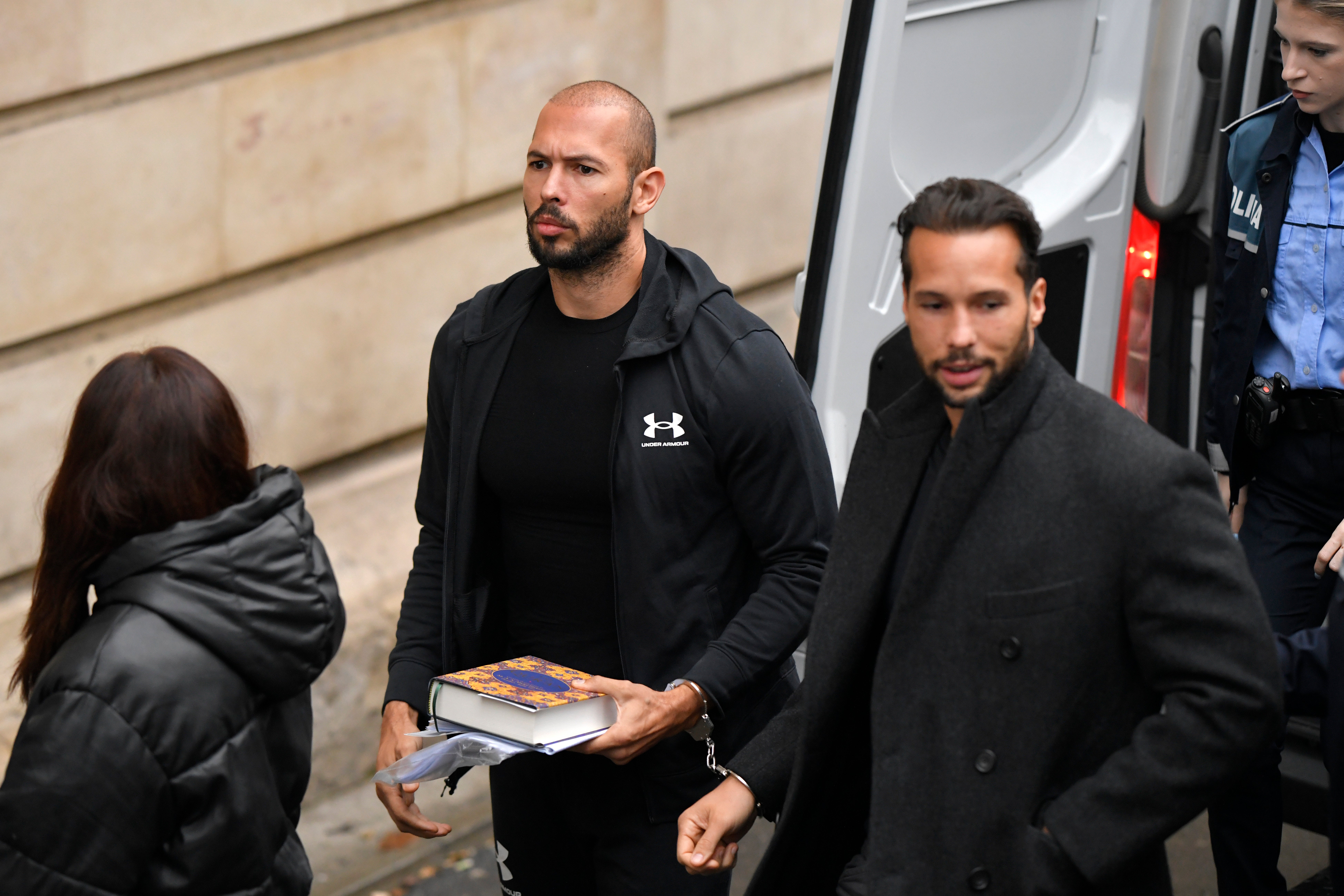 Andrew Tate, centre, and his brother Tristan, right, are brought by police officers to the Court of Appeal, in Bucharest, Romania