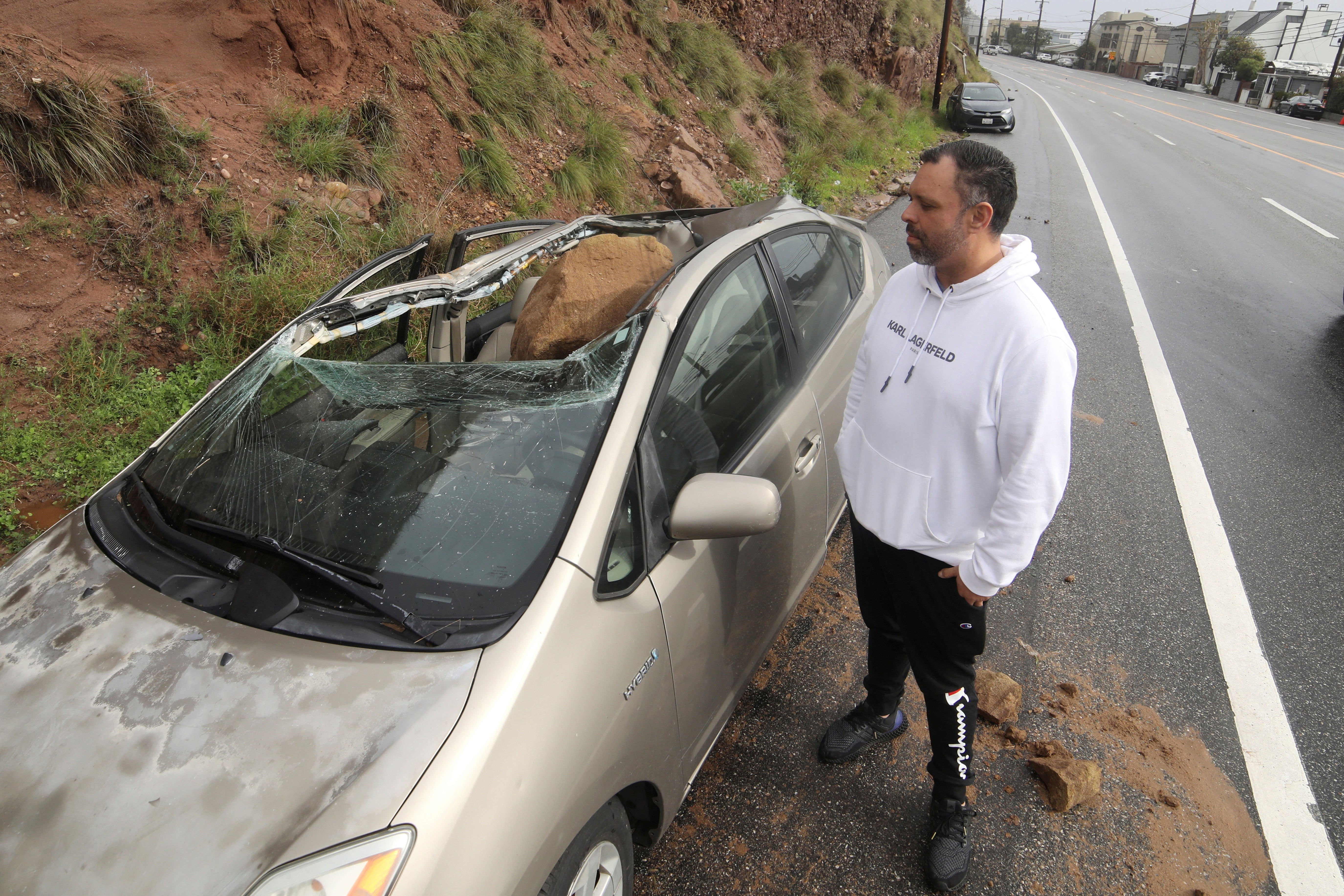 Owner Maurice Henao looks at the small boulder resting in his vehichle parked along the Pacific Coastal Highway in Malibu, California on January 10