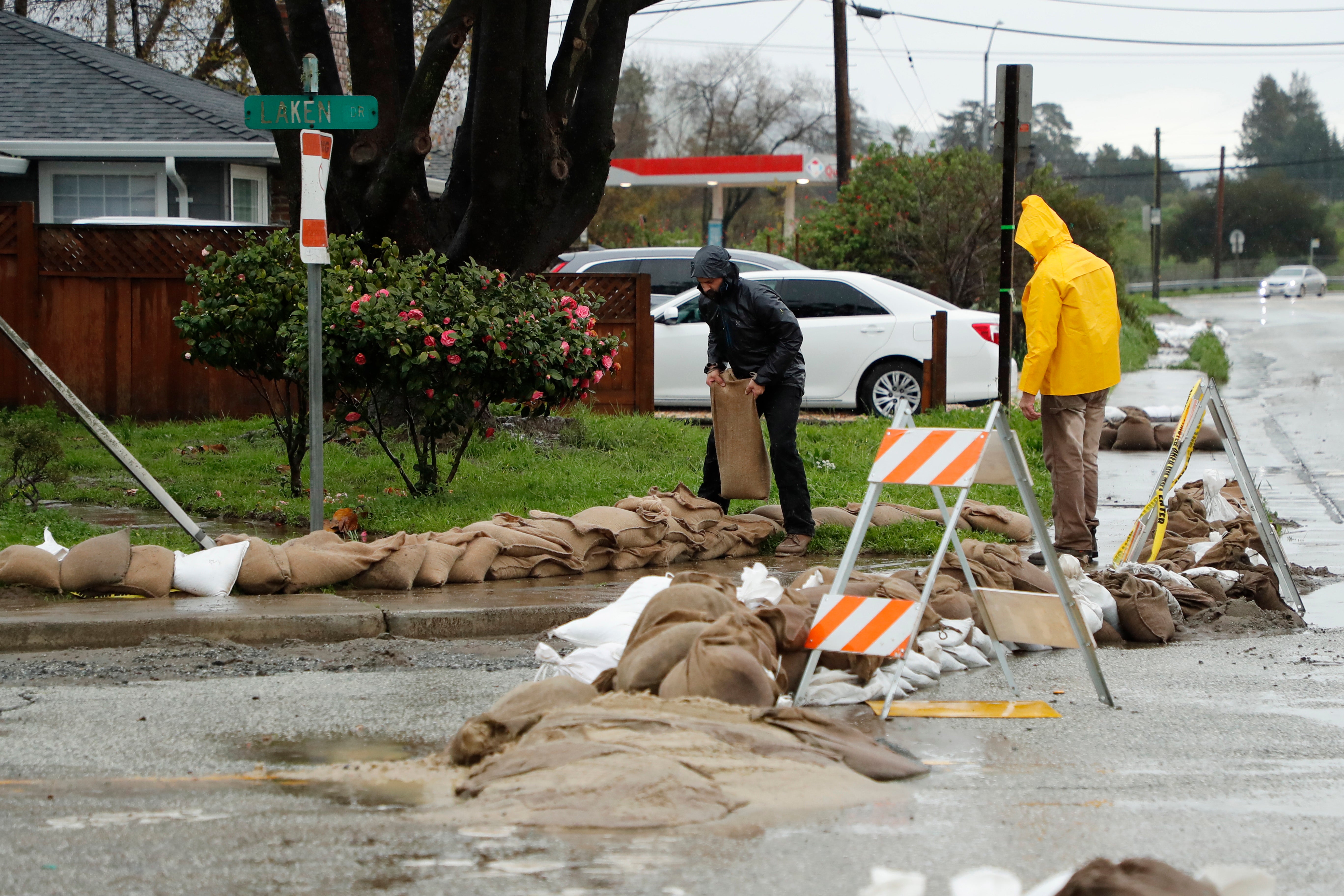 Residents stack sandbags around a home and along a neighborhood street in preparations for flooding from the next wave of storms