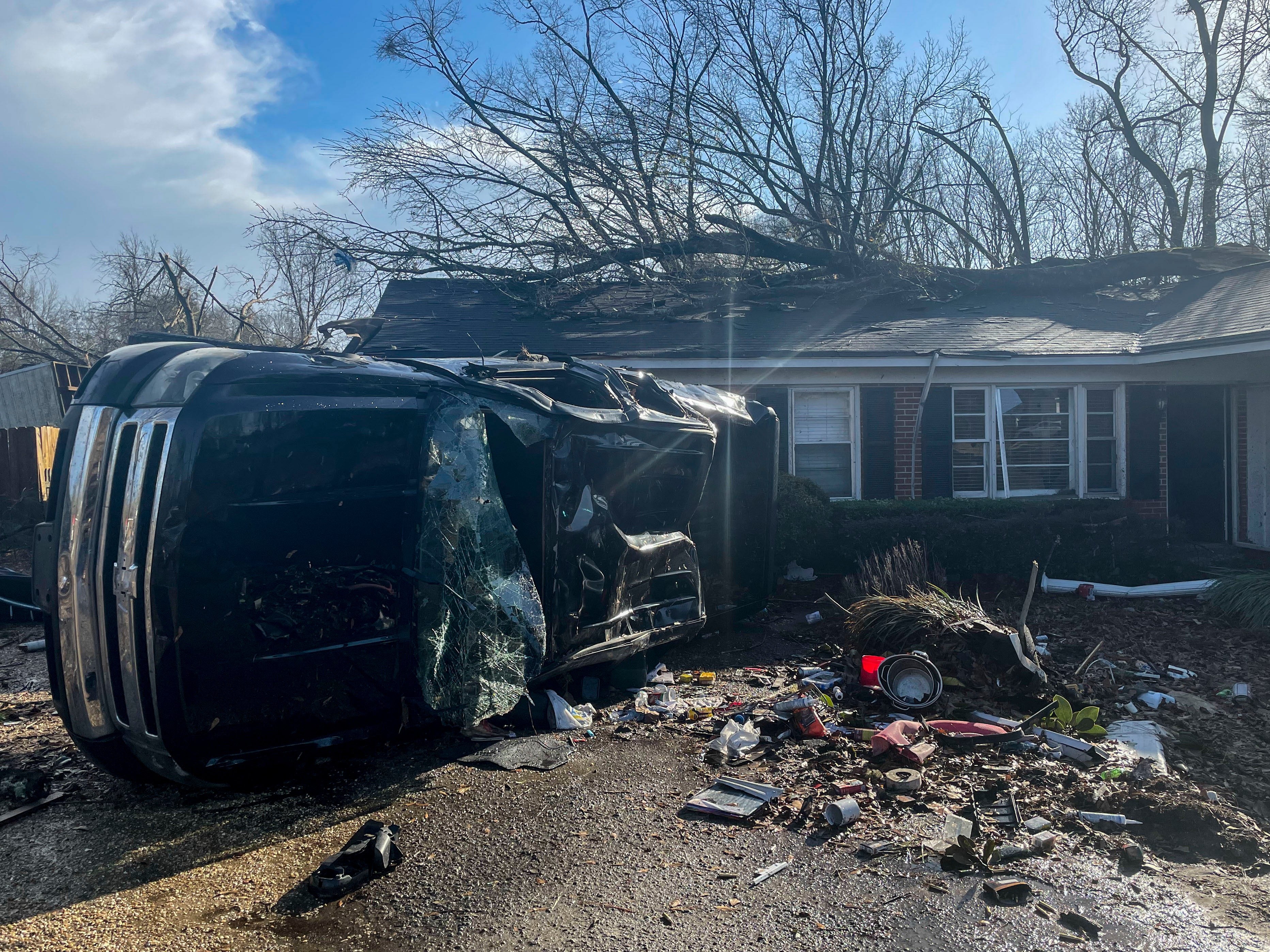 A damaged vehicle rests on its side in front of a home in Selma