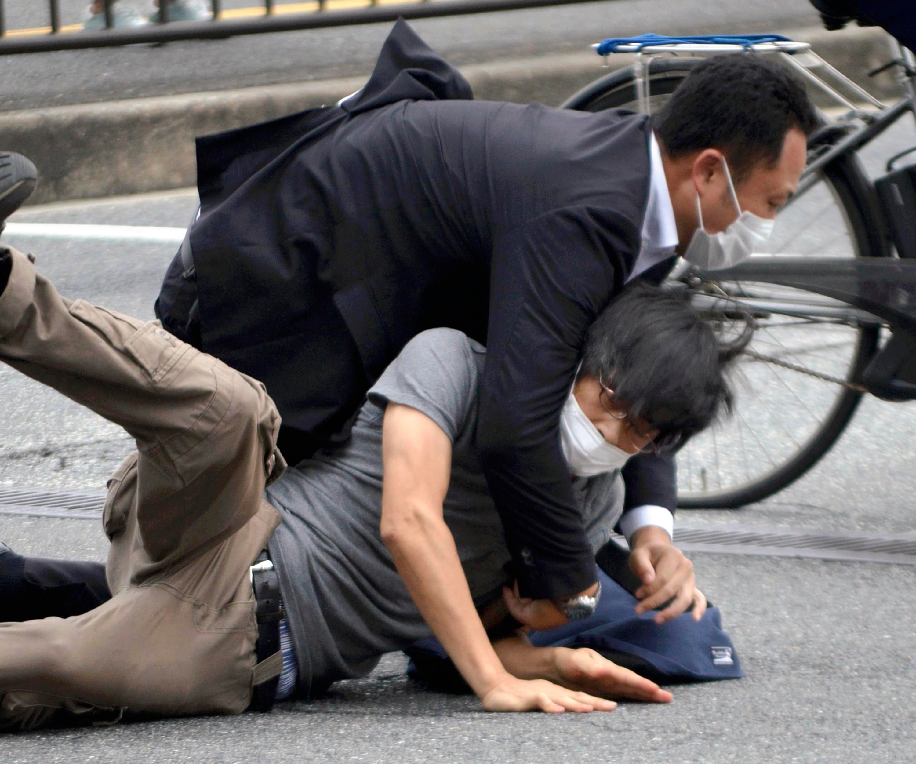 Tetsuya Yamagami, bottom, is detained near the site of gunshots in Nara Prefectur