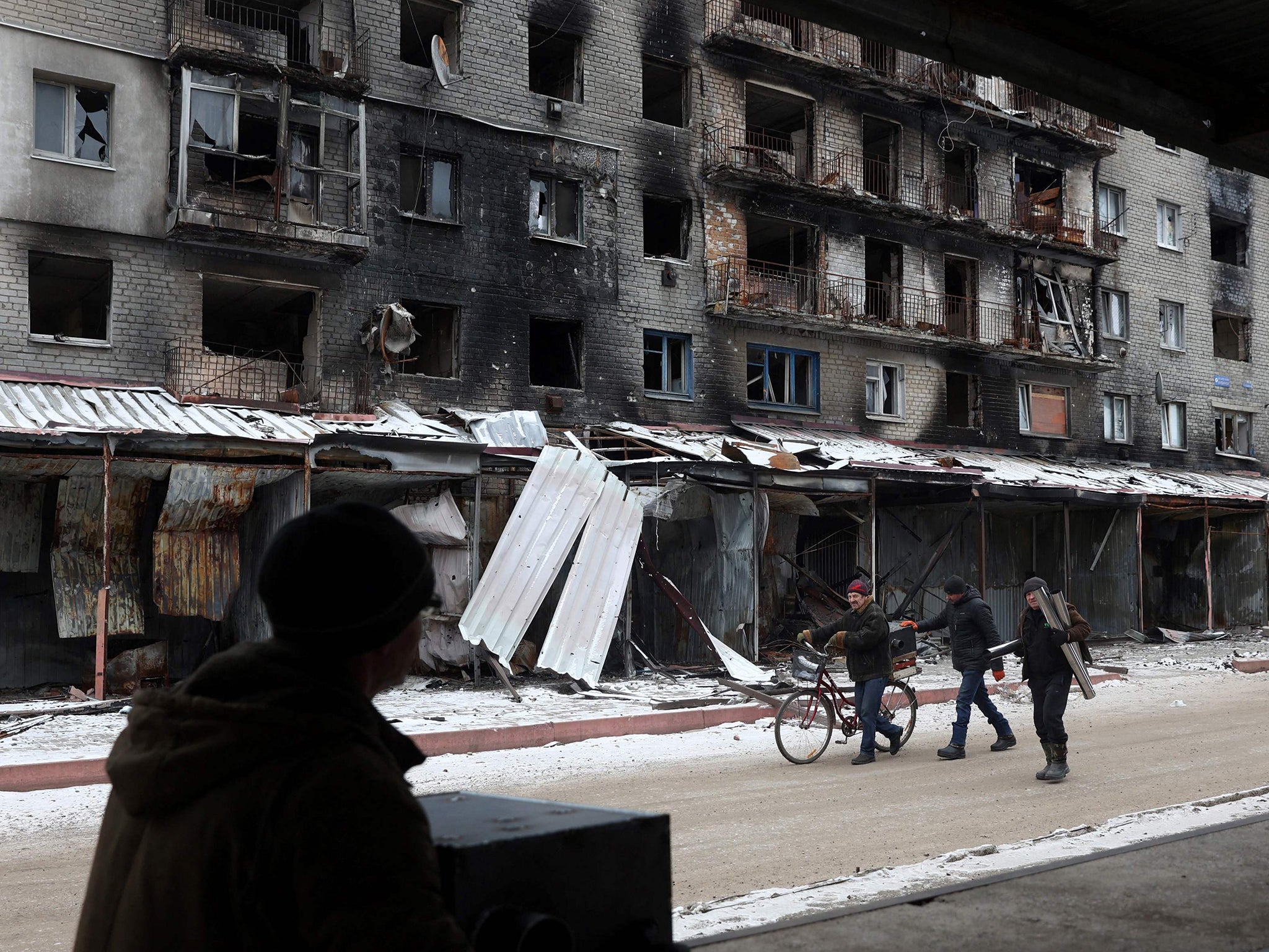 Local residents carry a potbelly stove received as part of humanitarian aid in the town of Siversk, Donetsk