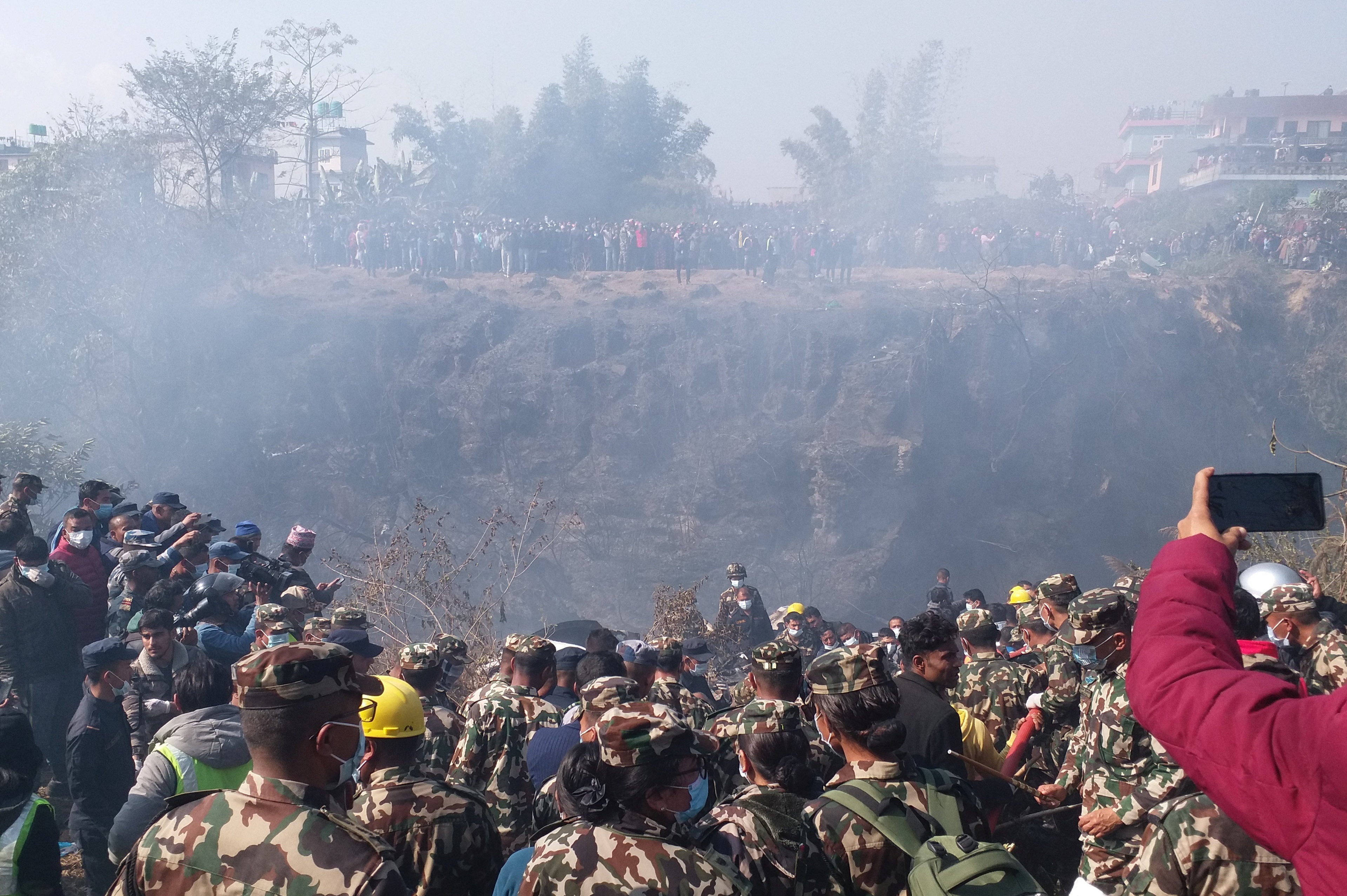 Crowds gather as rescue teams work to retrieve bodies at the crash site