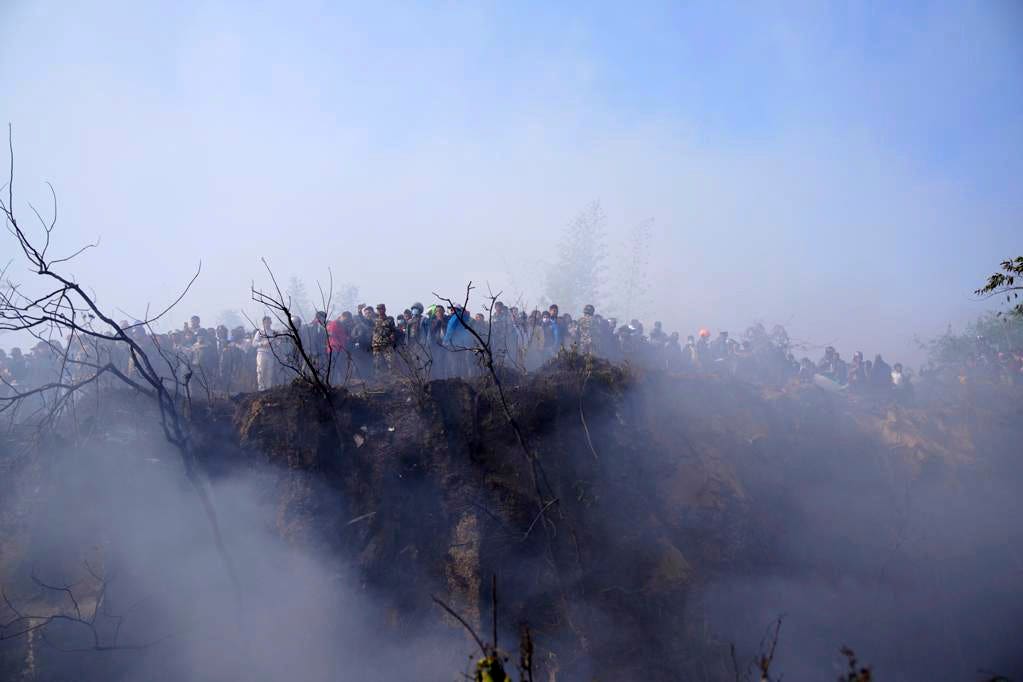 Locals near the wreckage of a passenger plane in Pokhara, Nepal (Yunish Gurung/AP)