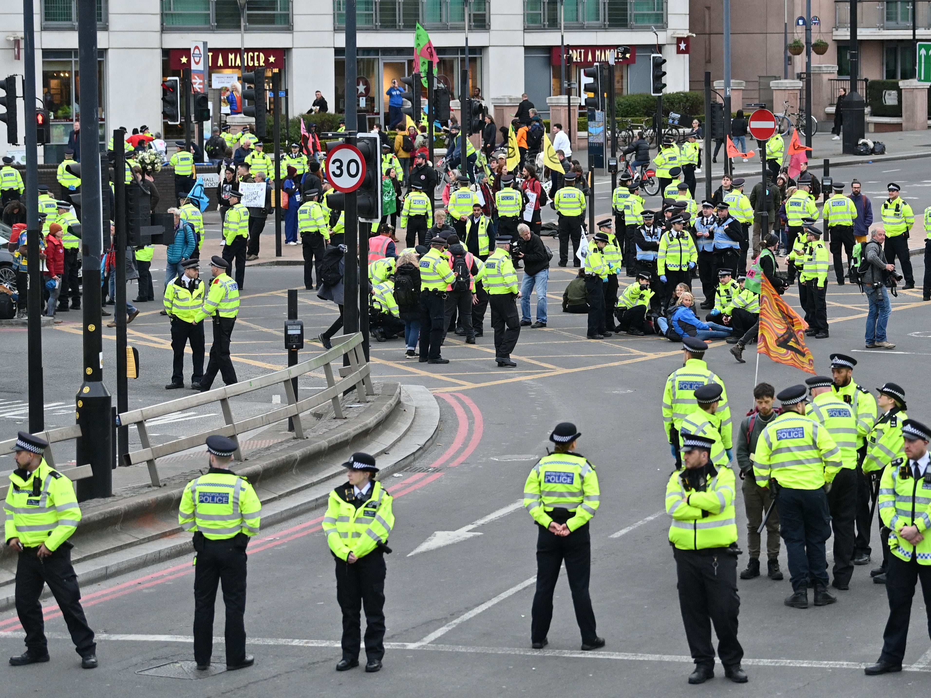 Police officers surround activists from the climate change protester group Extinction Rebellion as they demonstrate on the south side of Vauzhall Bridge in London on April 10, 2022