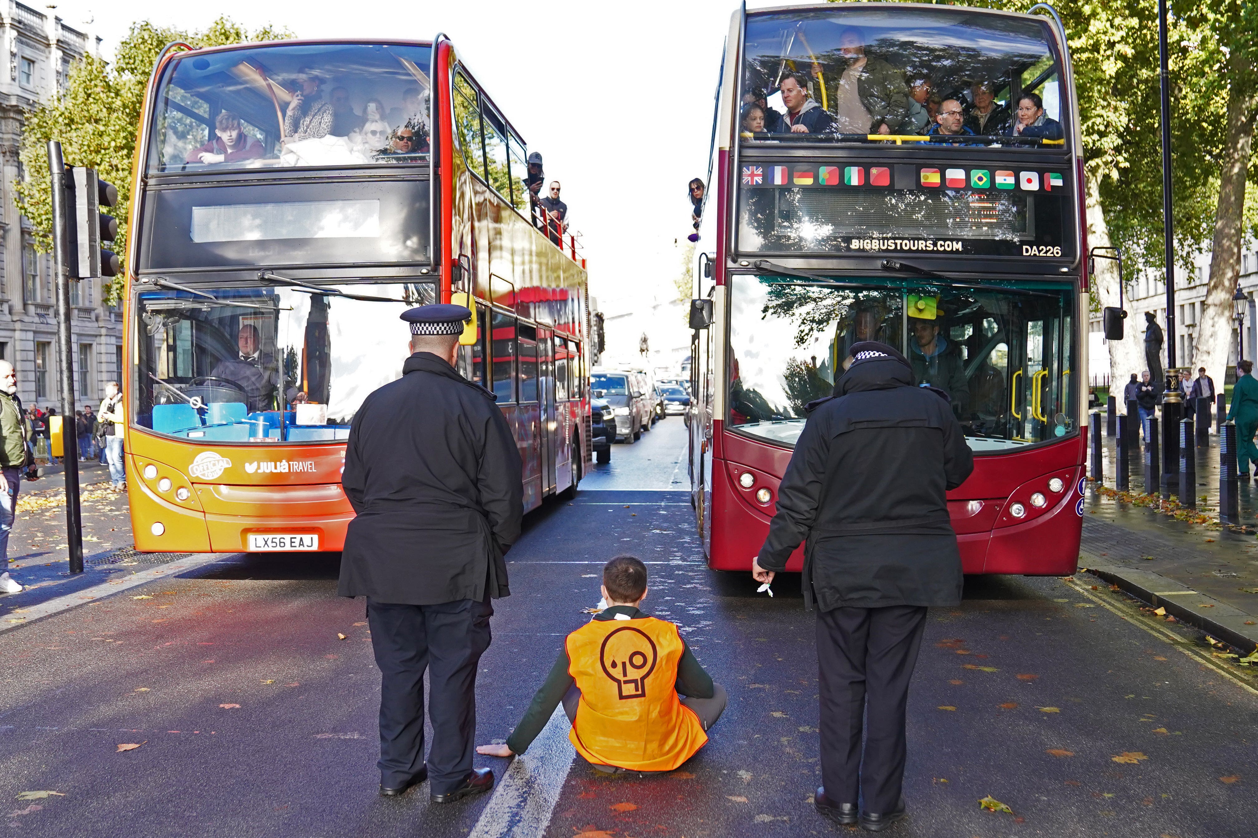 A Just Stop Oil activist sits in the middle of Whitehall in Westminster, London (Stefan Rousseau/PA)