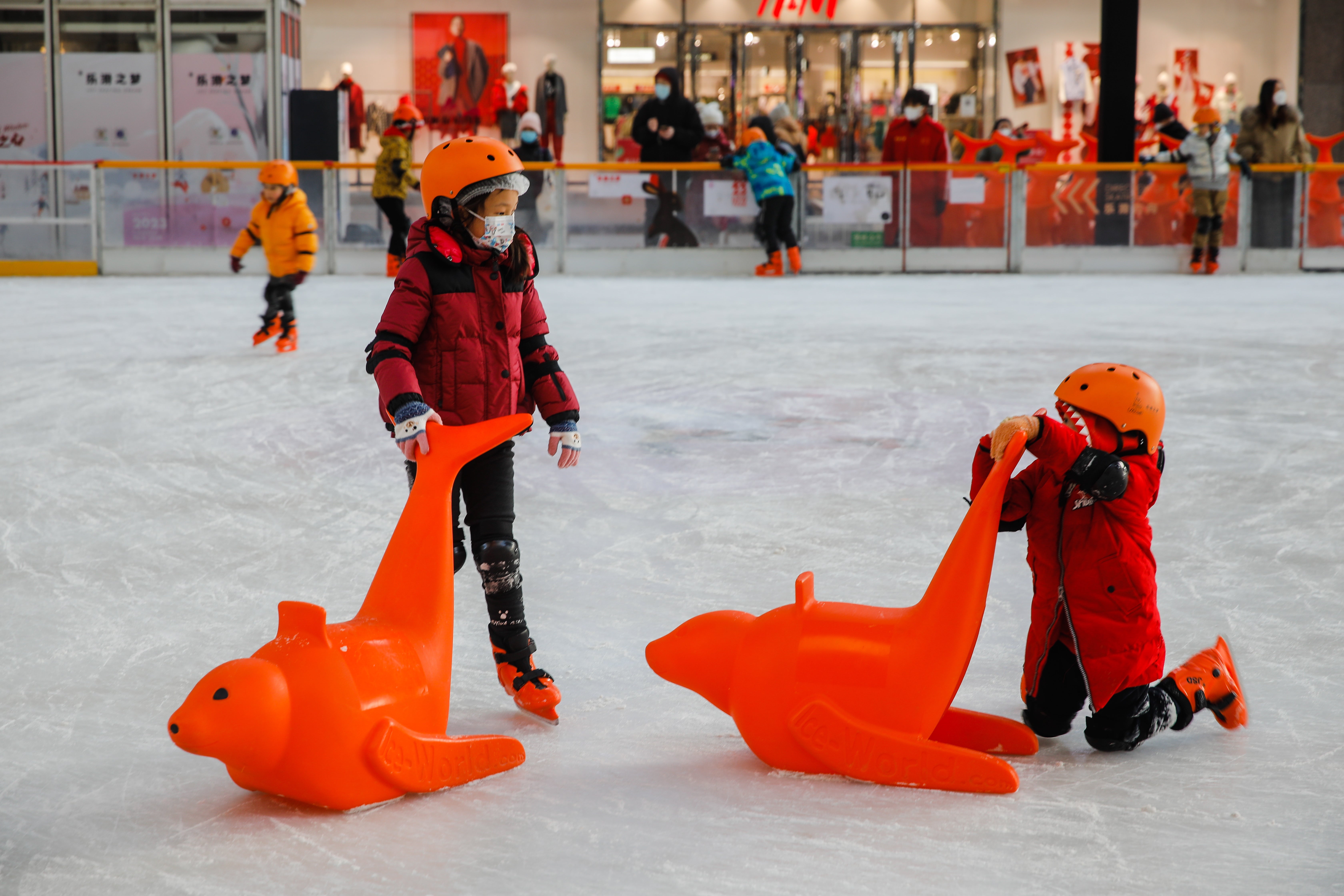 Children wearing face coverings skate at an ice rink in Beijing