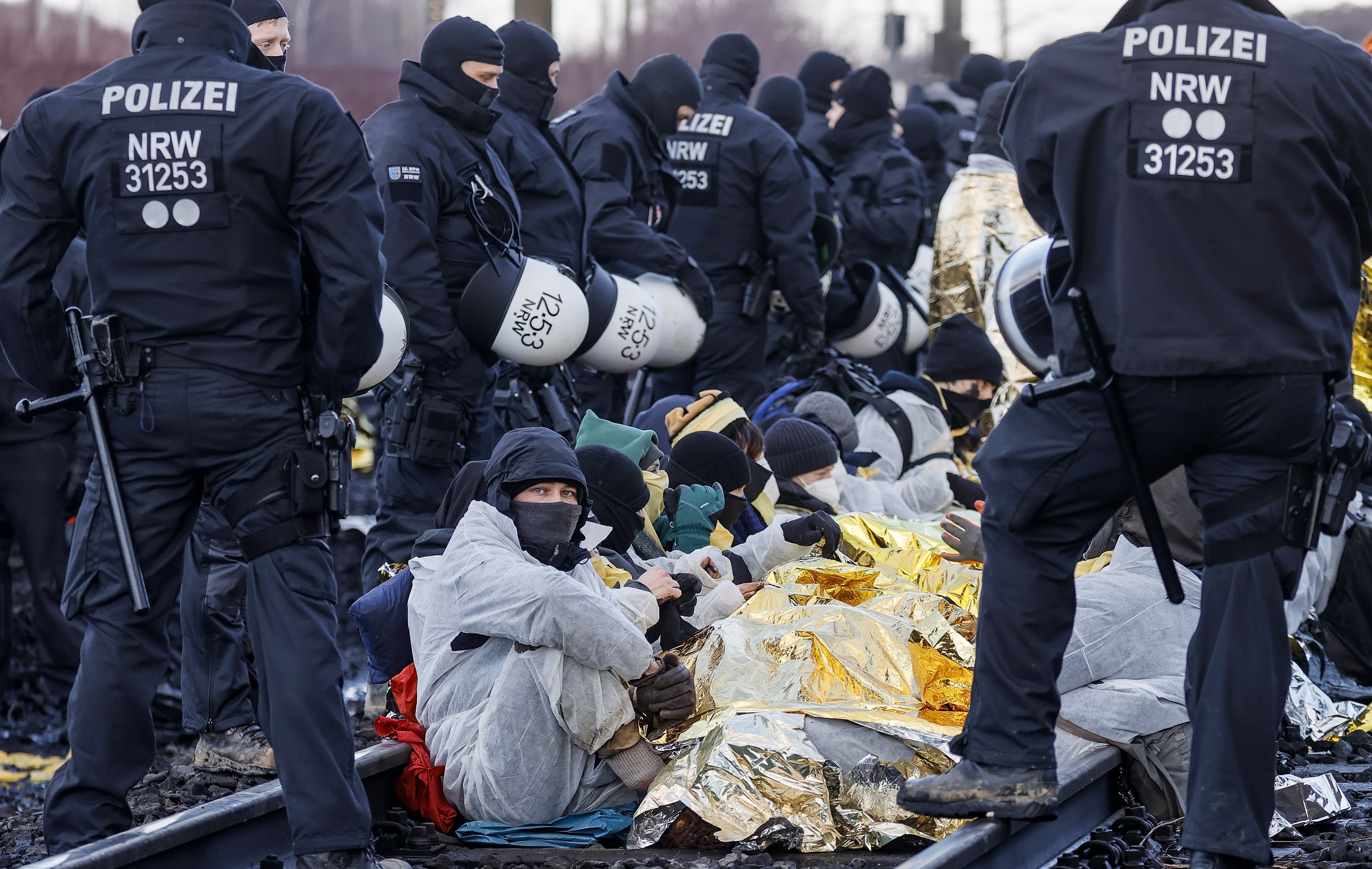 Police officers stand next to activists blocking the tracks over which the lignite is transported from the Garzweiler open-cast mine on Tuesday