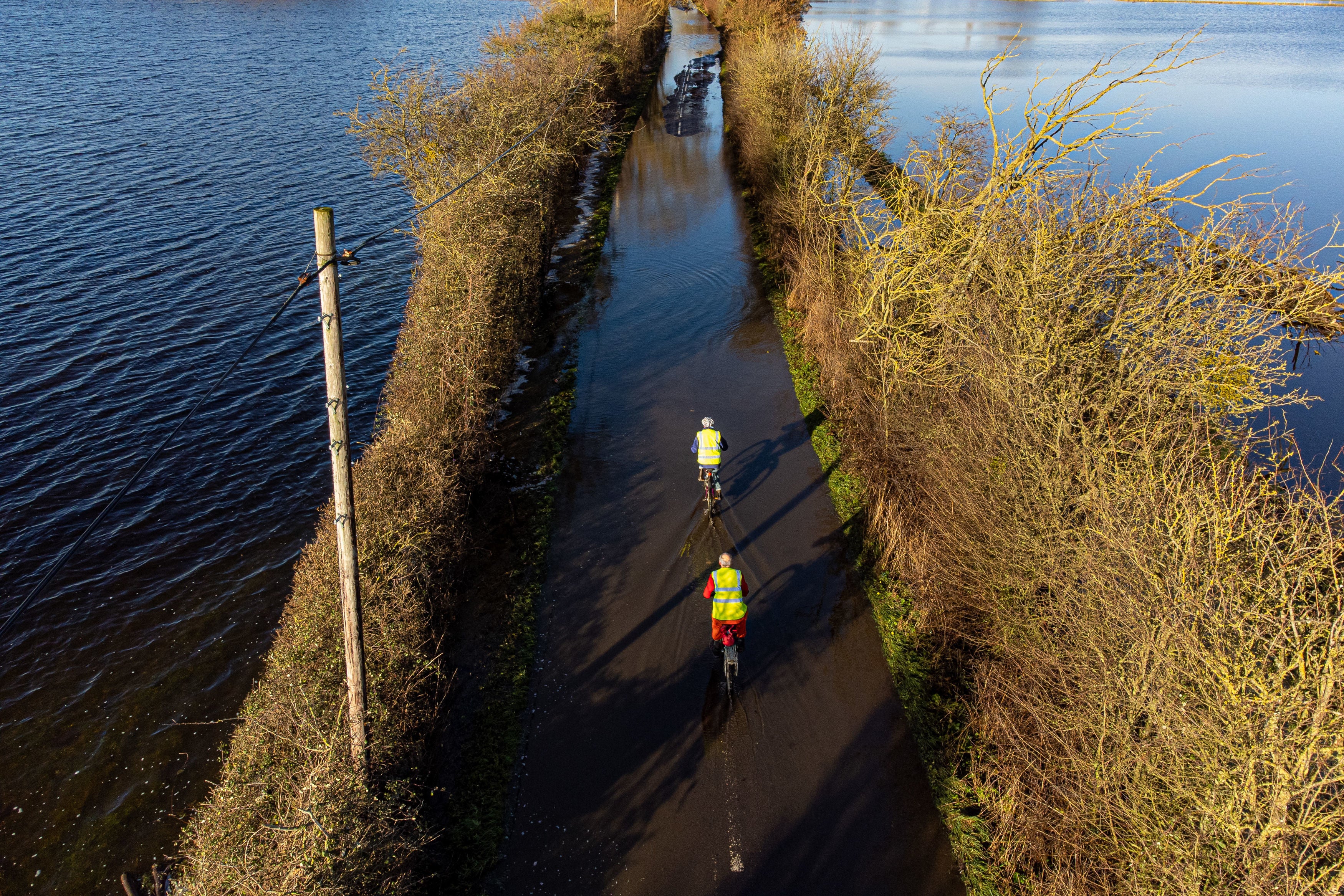 Cyclists pedal through floodwater near Muchelney, Somerset