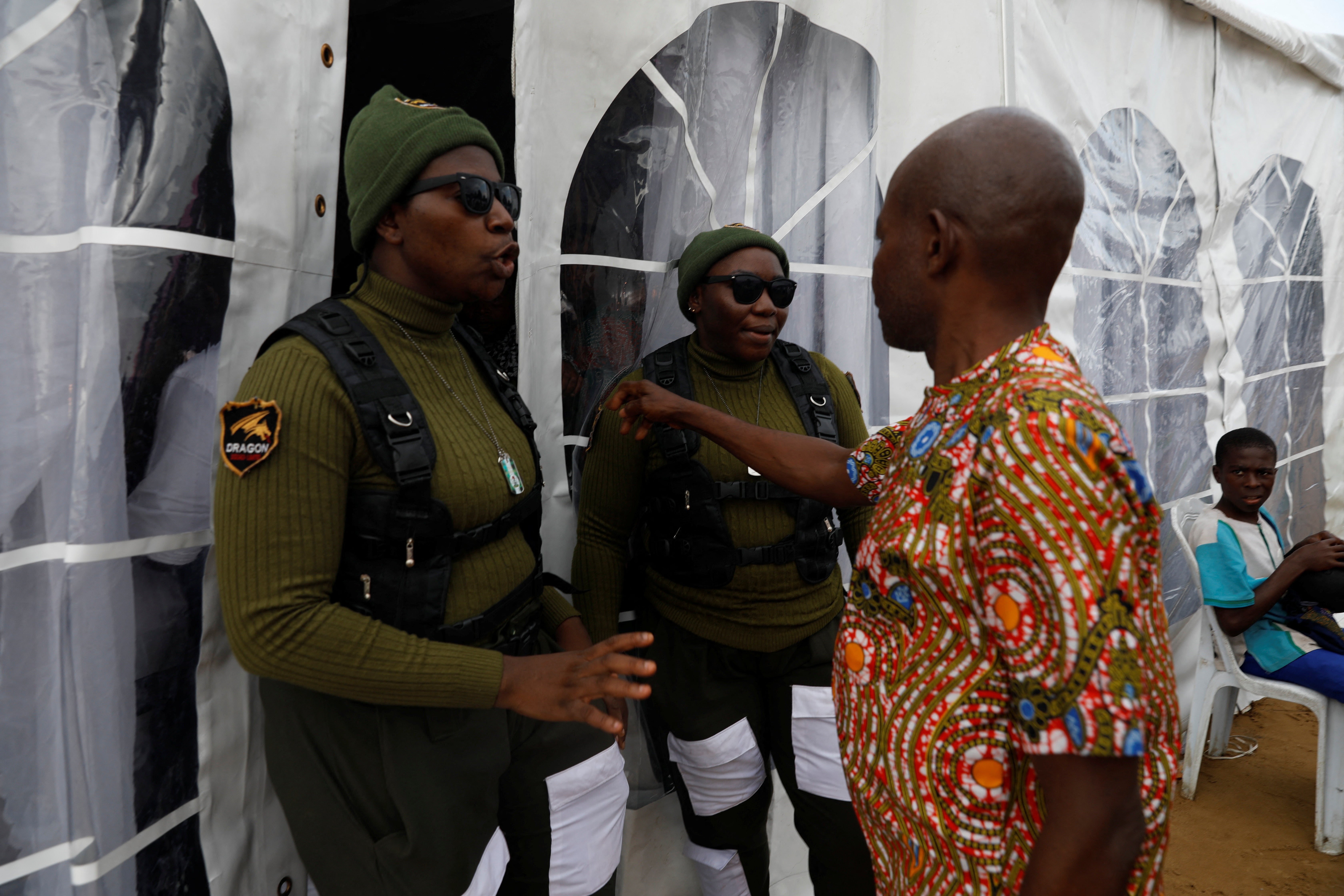 Mfoniso Peter and Glory Anthony speak to a man at the entrance of a funeral